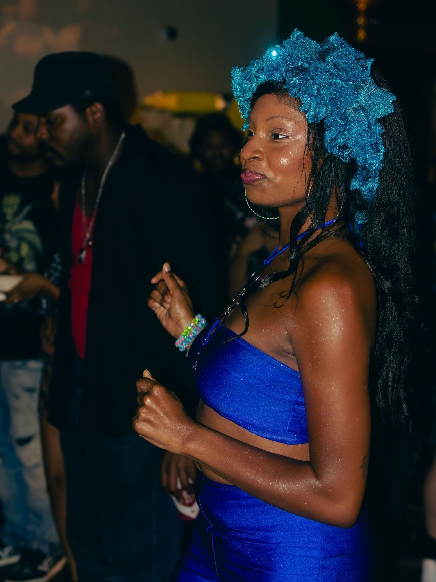 Dancer in vibrant blue outfit with turquoise hair enjoying music at nightclub.