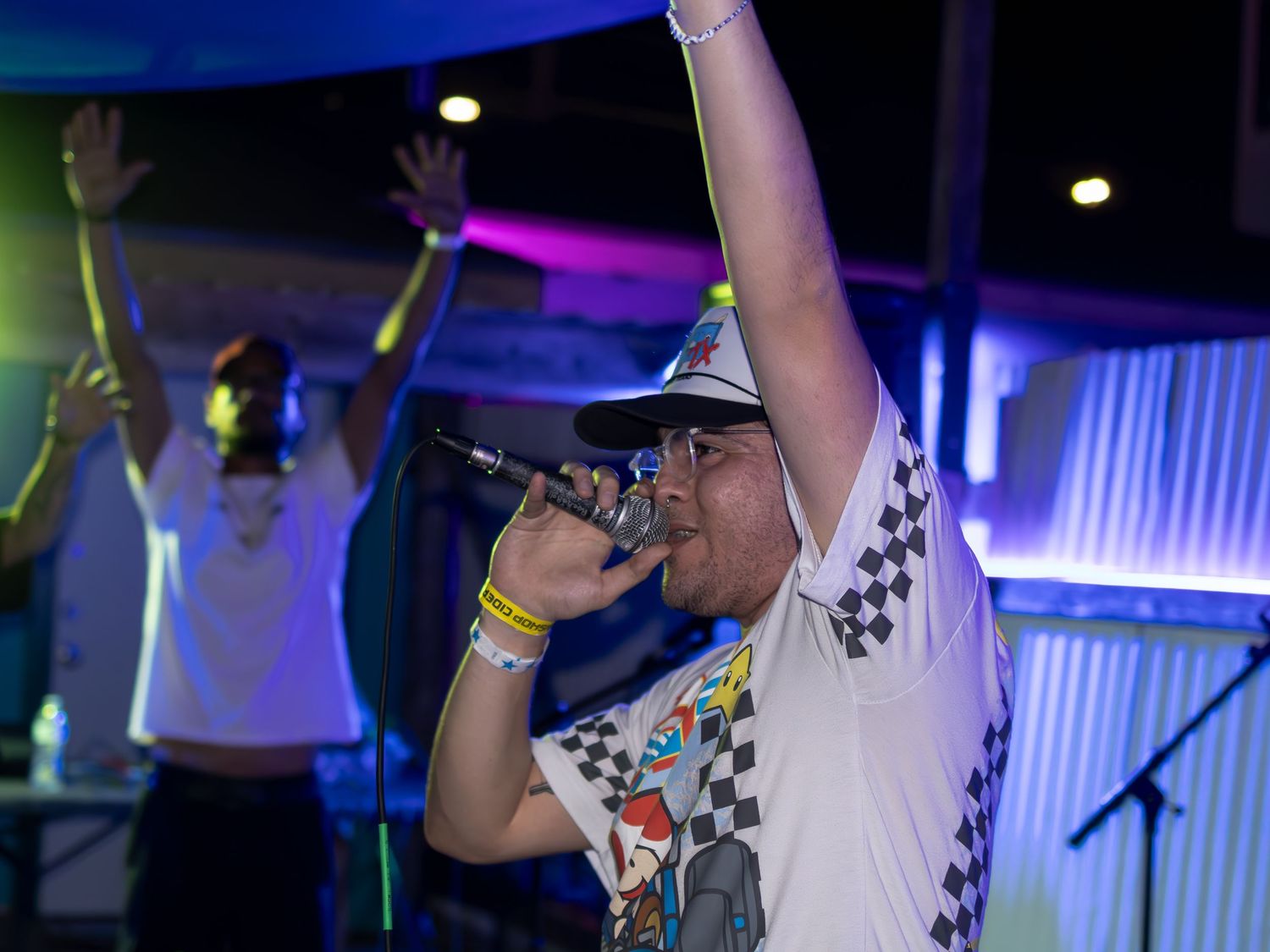 Dynamic stage performance with dramatic blue lighting and gaming-inspired outfit.