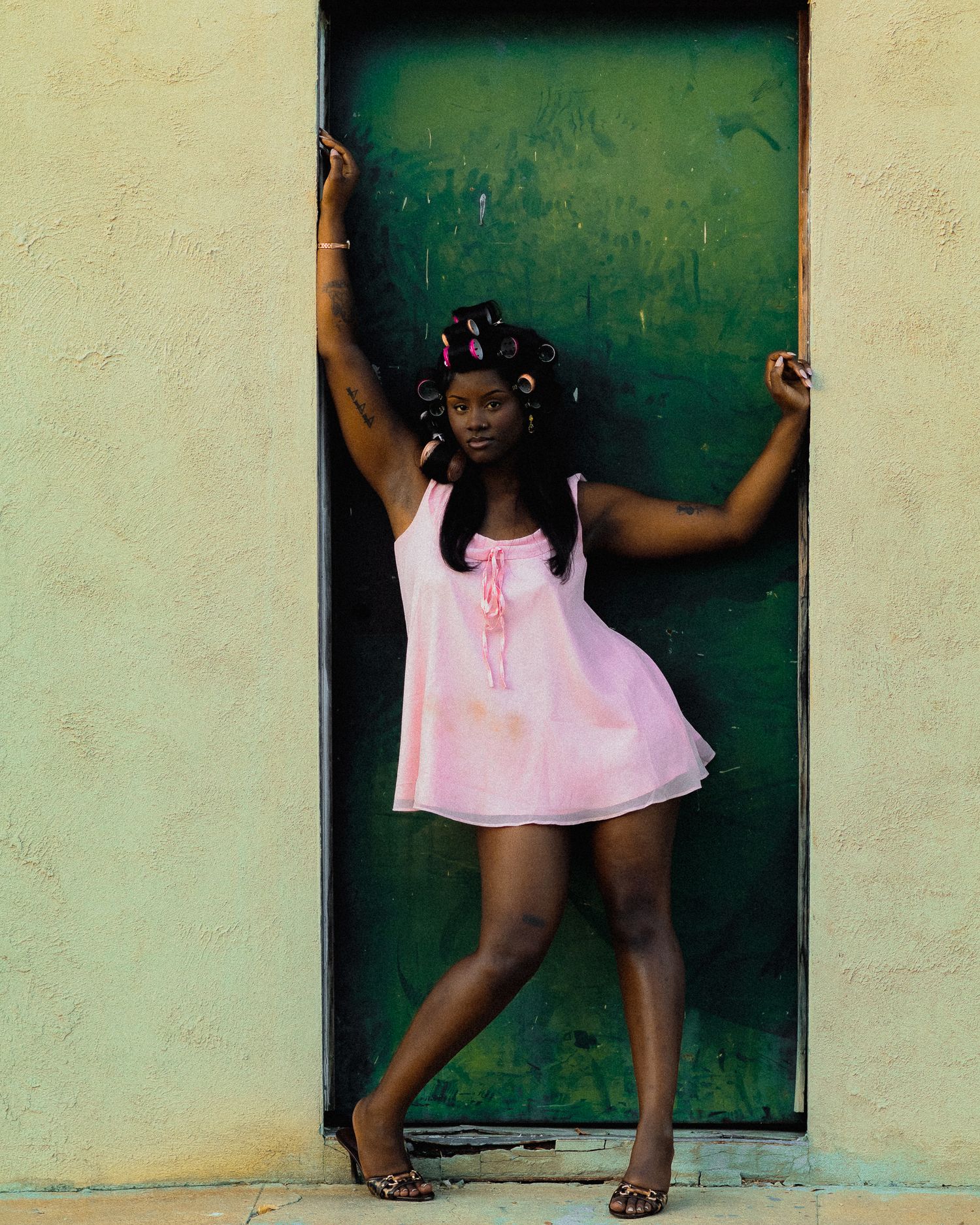 Dynamic movement sequence photographed against a green door and cream wall.