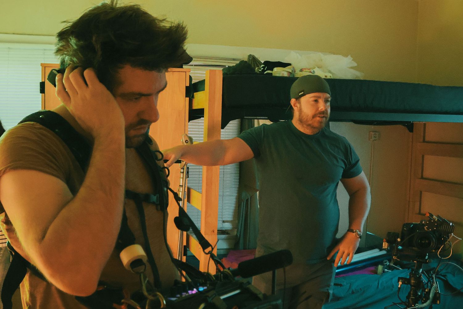 Film production crew working with equipment in moody green lighting.