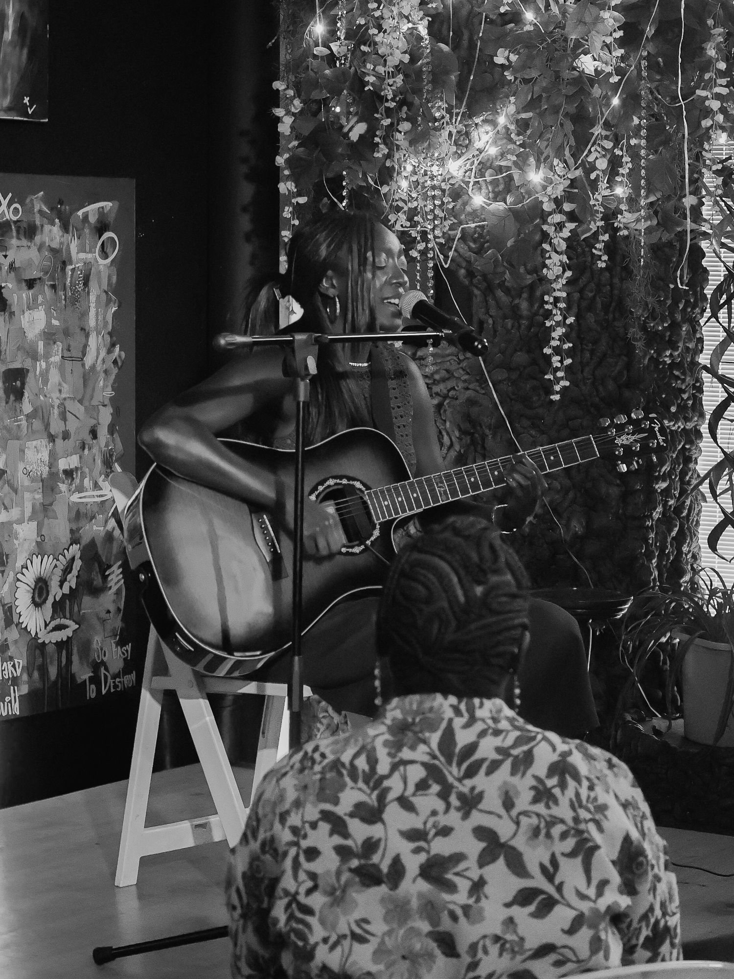 Monochrome image shows musical performance setup with guitar and decorative elements in intimate venue.