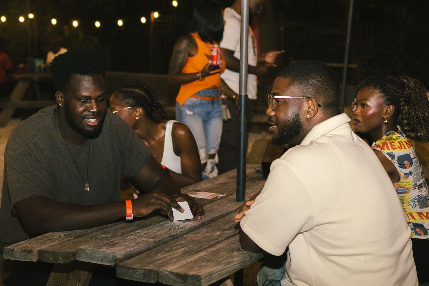 People socializing at outdoor tables during an evening gathering.