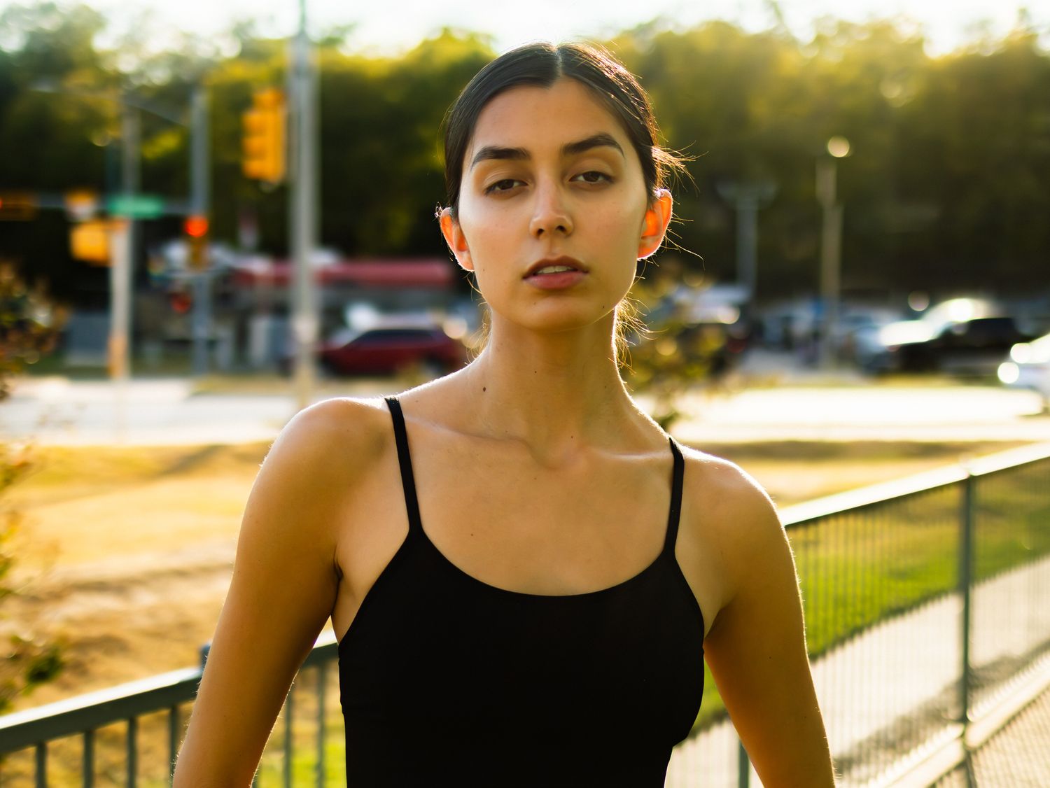 Athletic form in black sports bra captured during sunset against urban backdrop.
