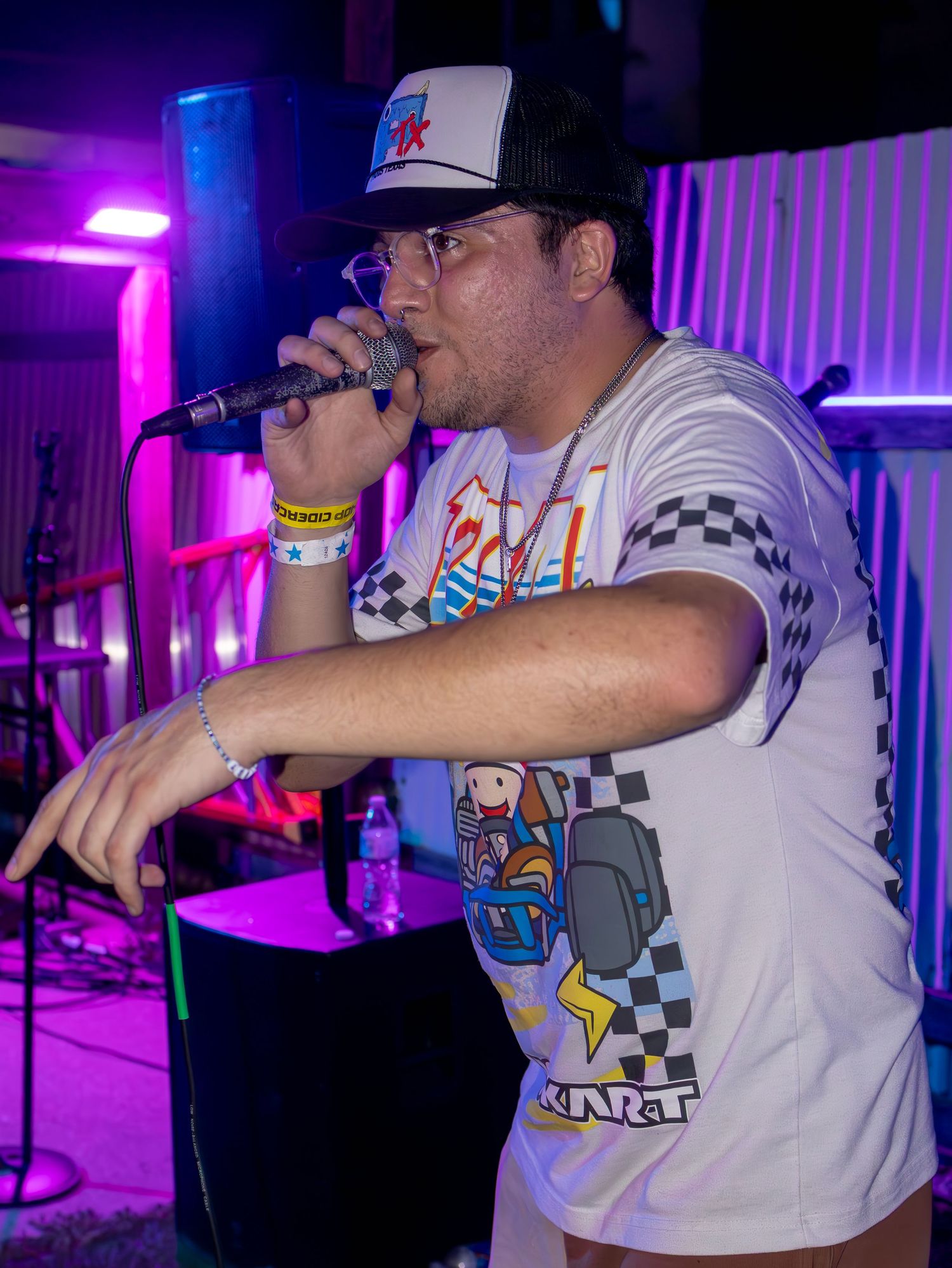 Singer in Nintendo gaming shirt performing energetically under purple stage lights.