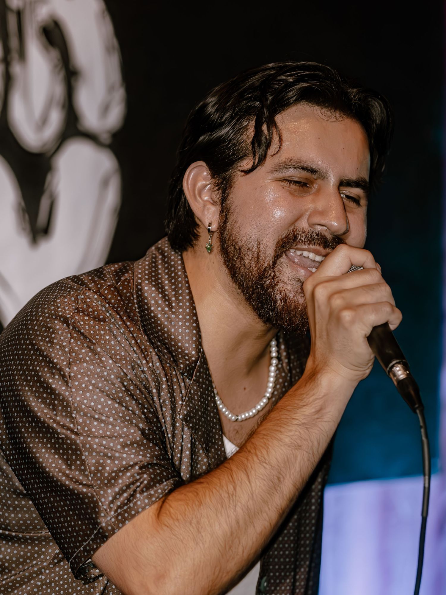 Vocalist delivers emotional performance while gripping microphone in dimly lit venue.