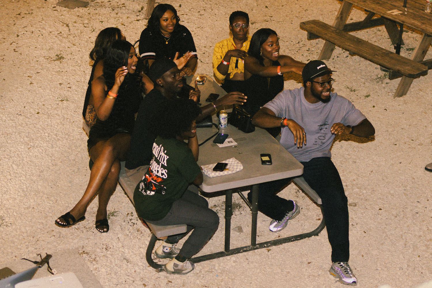 Group gathering outdoors at dusk with casual seating arrangements.