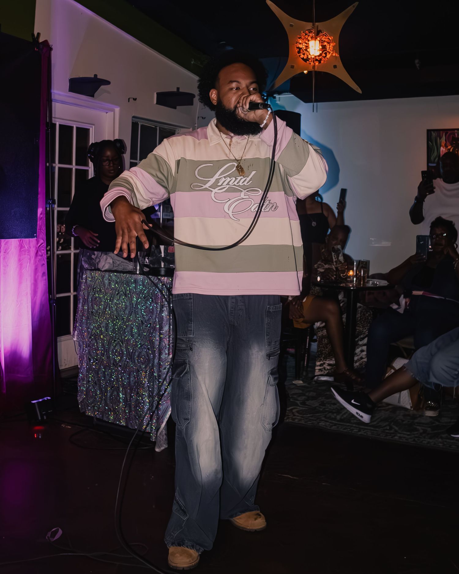 Growchild. in striped sweater energetically singing on stage with decorative lighting.