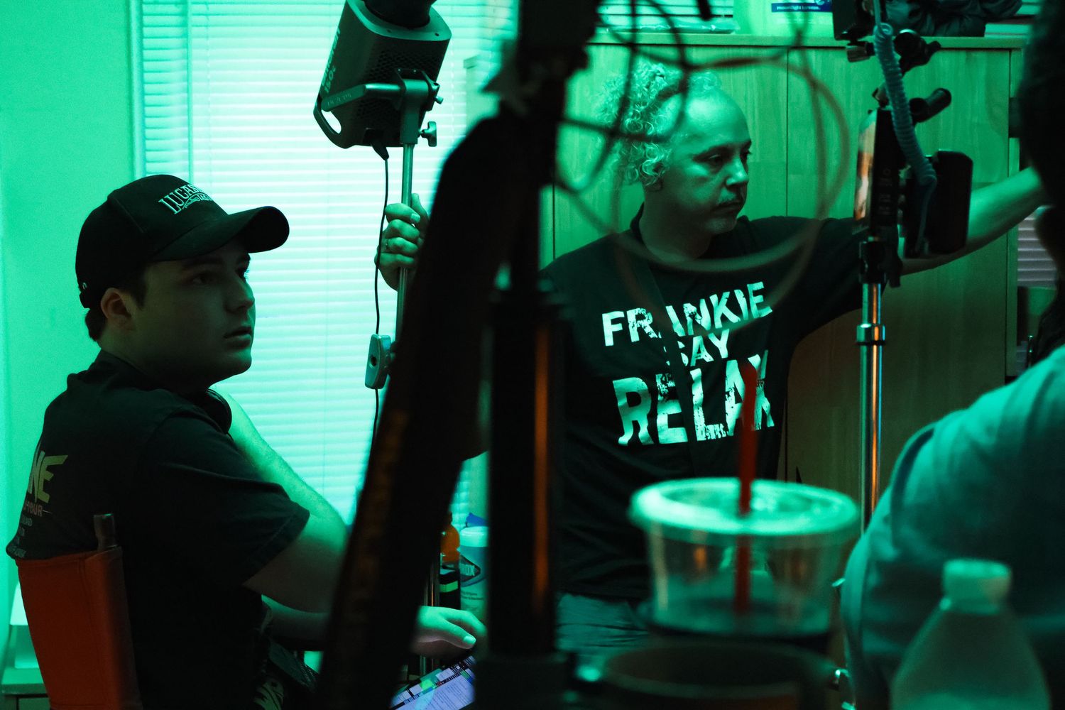 Production crew working with equipment under intense green lighting effects.