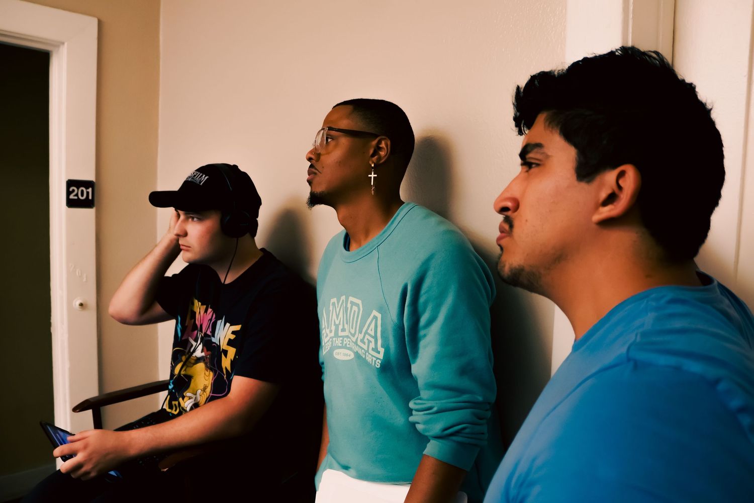 People lined up against a wall in a recording studio environment.