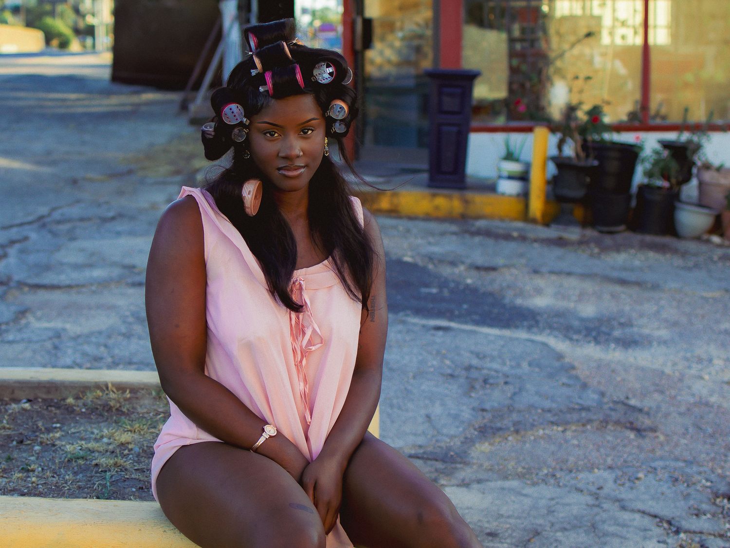 A person sits casually on a painted curb in an urban setting.