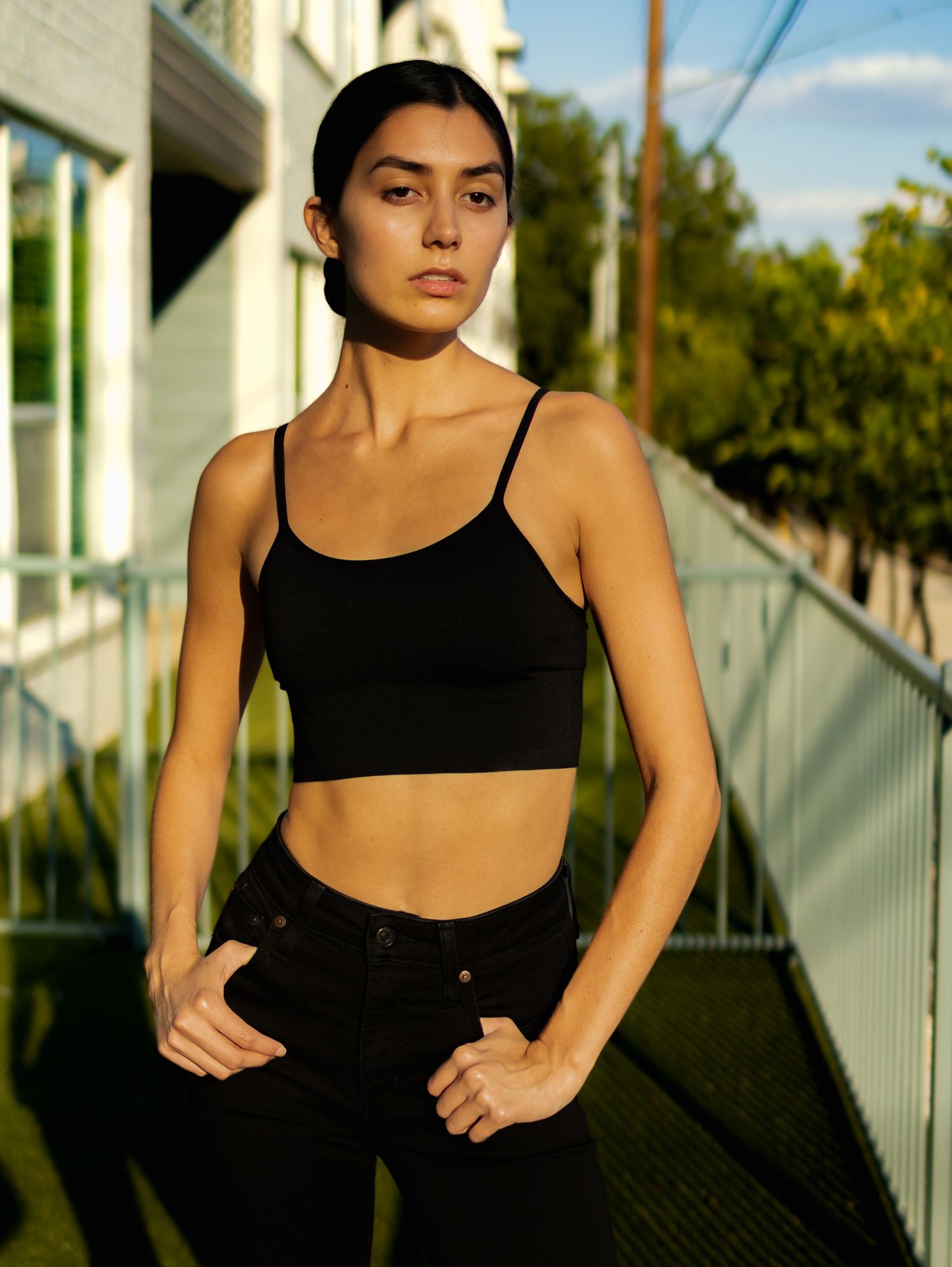 Athletic silhouette stretches outdoors against white building in afternoon sunlight.