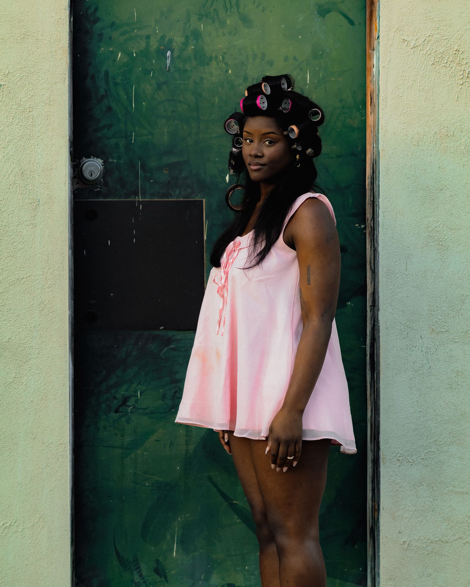 Artistic photoshoot sequence featuring pink clothing against contrasting green doorway.