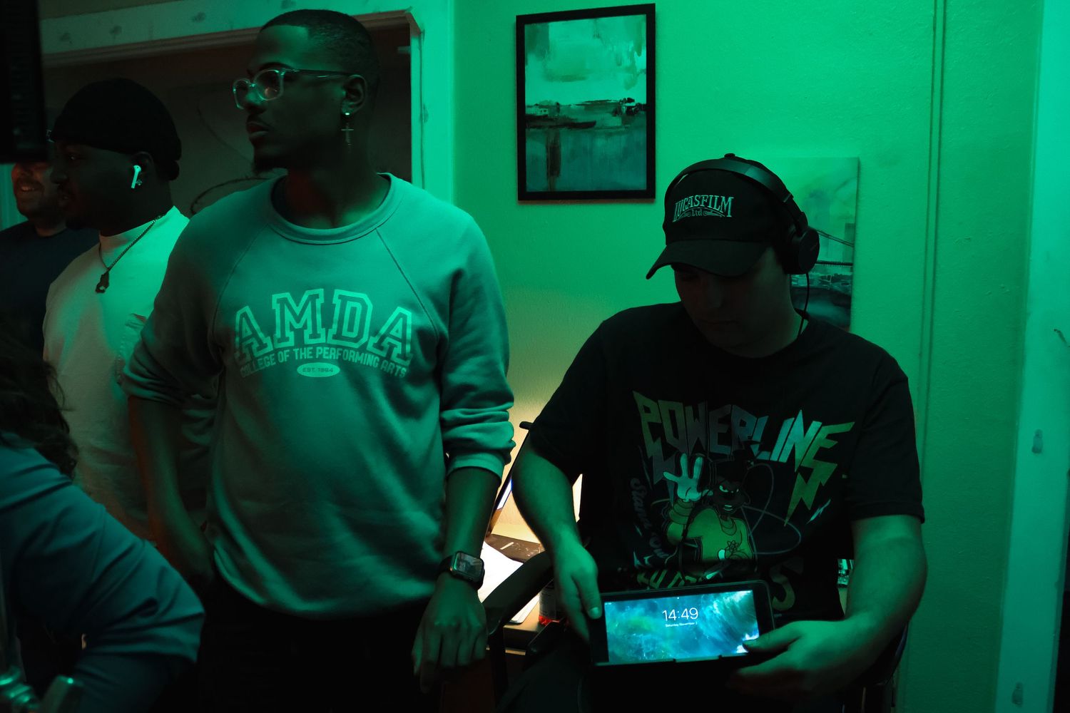 Video production scene bathed in green lighting shows crew members with equipment.