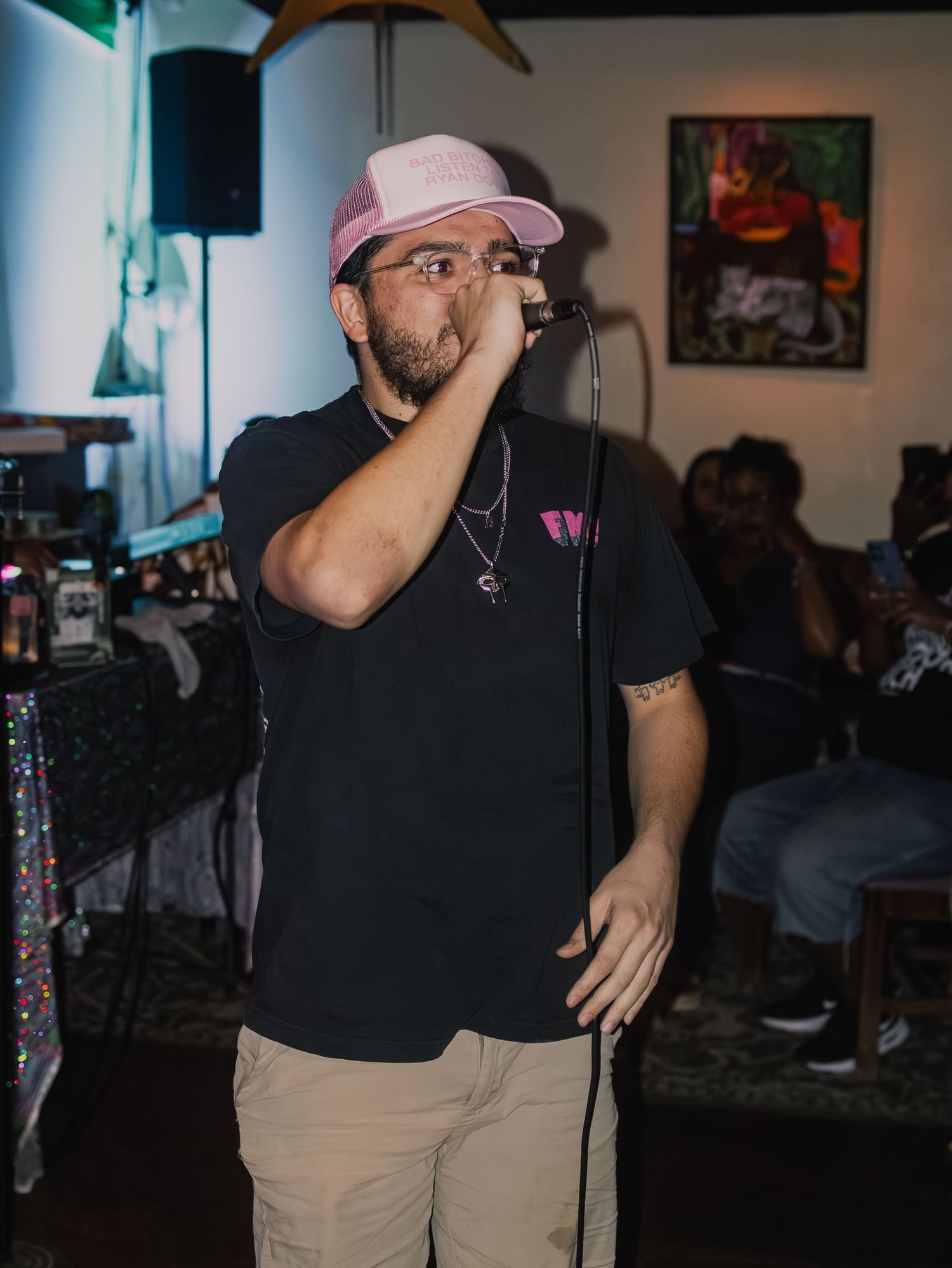 Live music performance in small indoor venue with artwork displayed on walls.