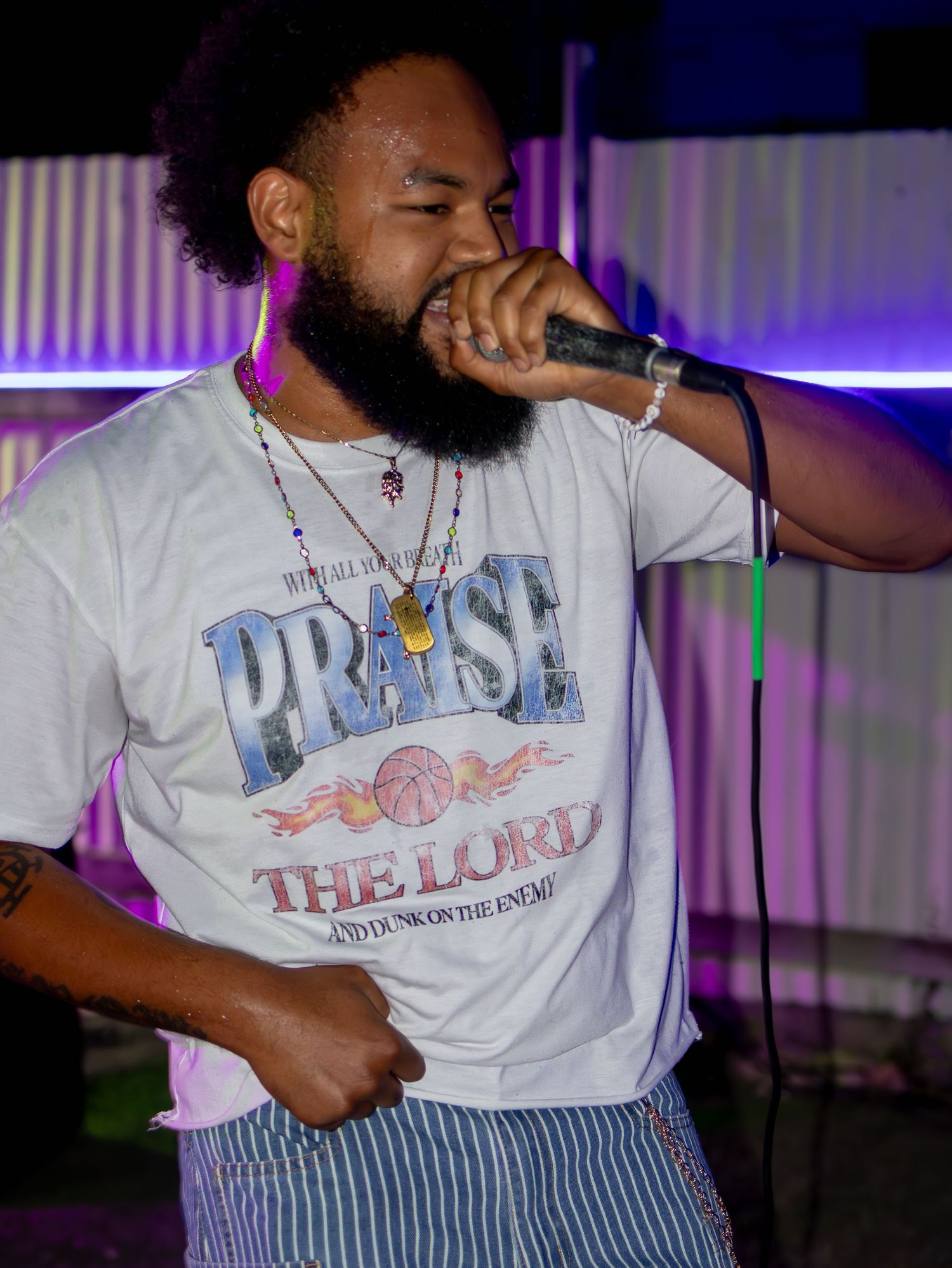 Artist wearing a vintage-style graphic t-shirt performs under colorful stage lights.
