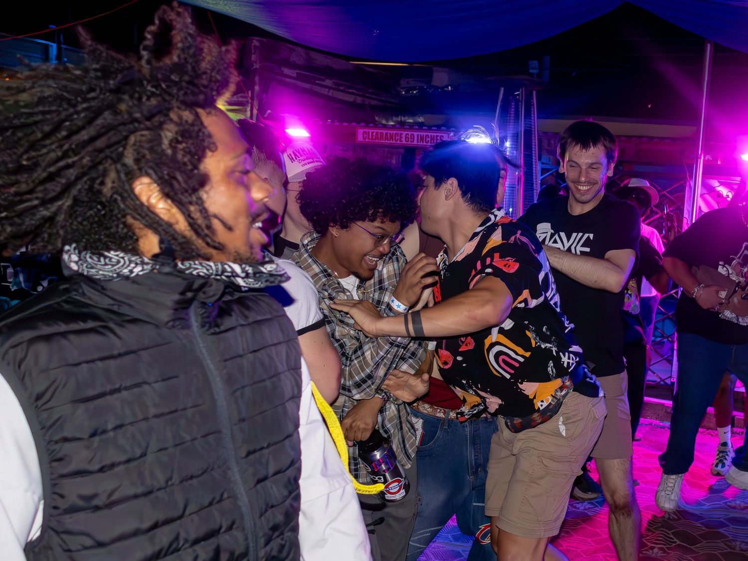 Concert attendees moving to the music under colorful stage lights at night.