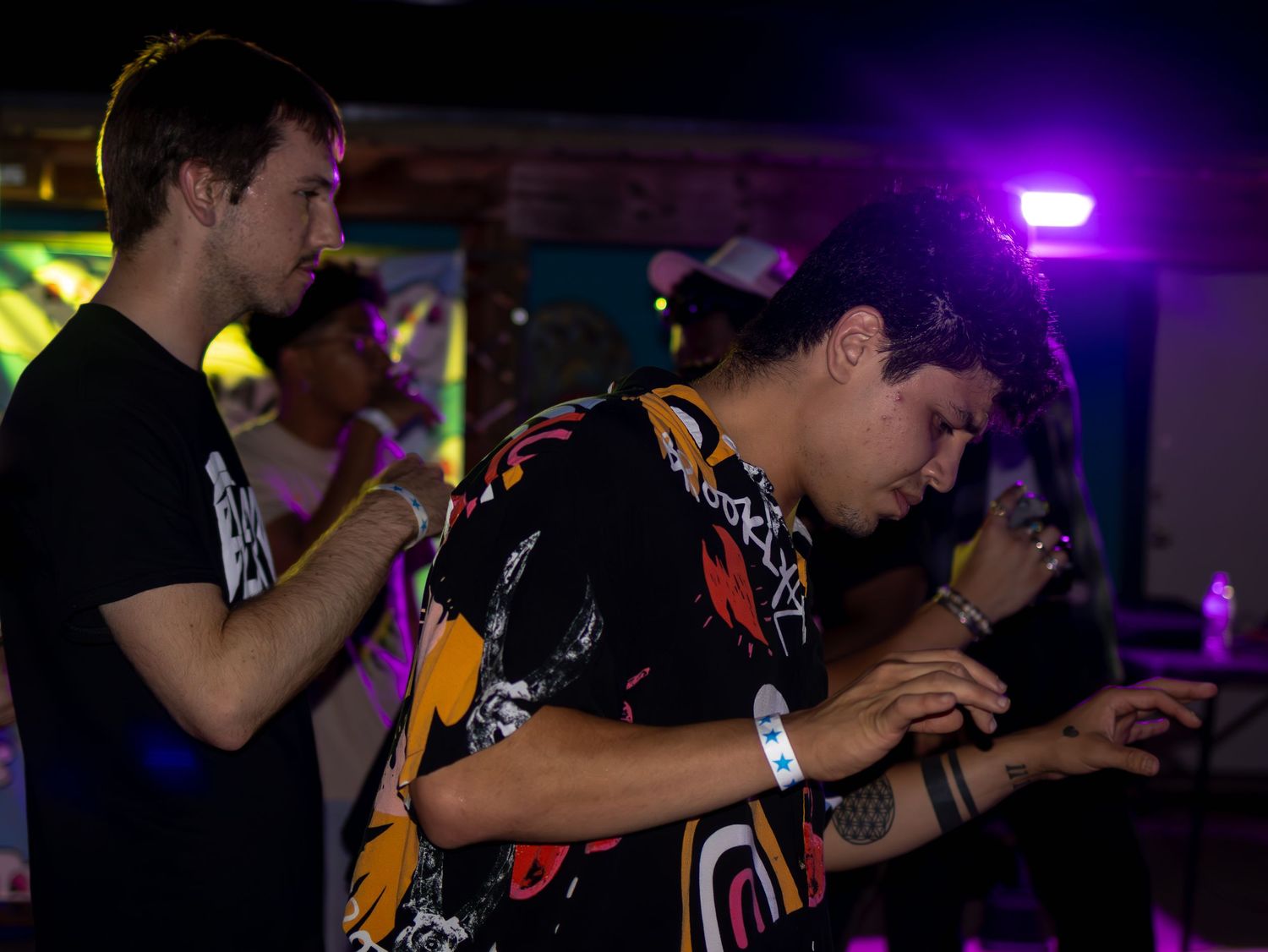 Energetic audience members dancing with hands up at a concert venue.