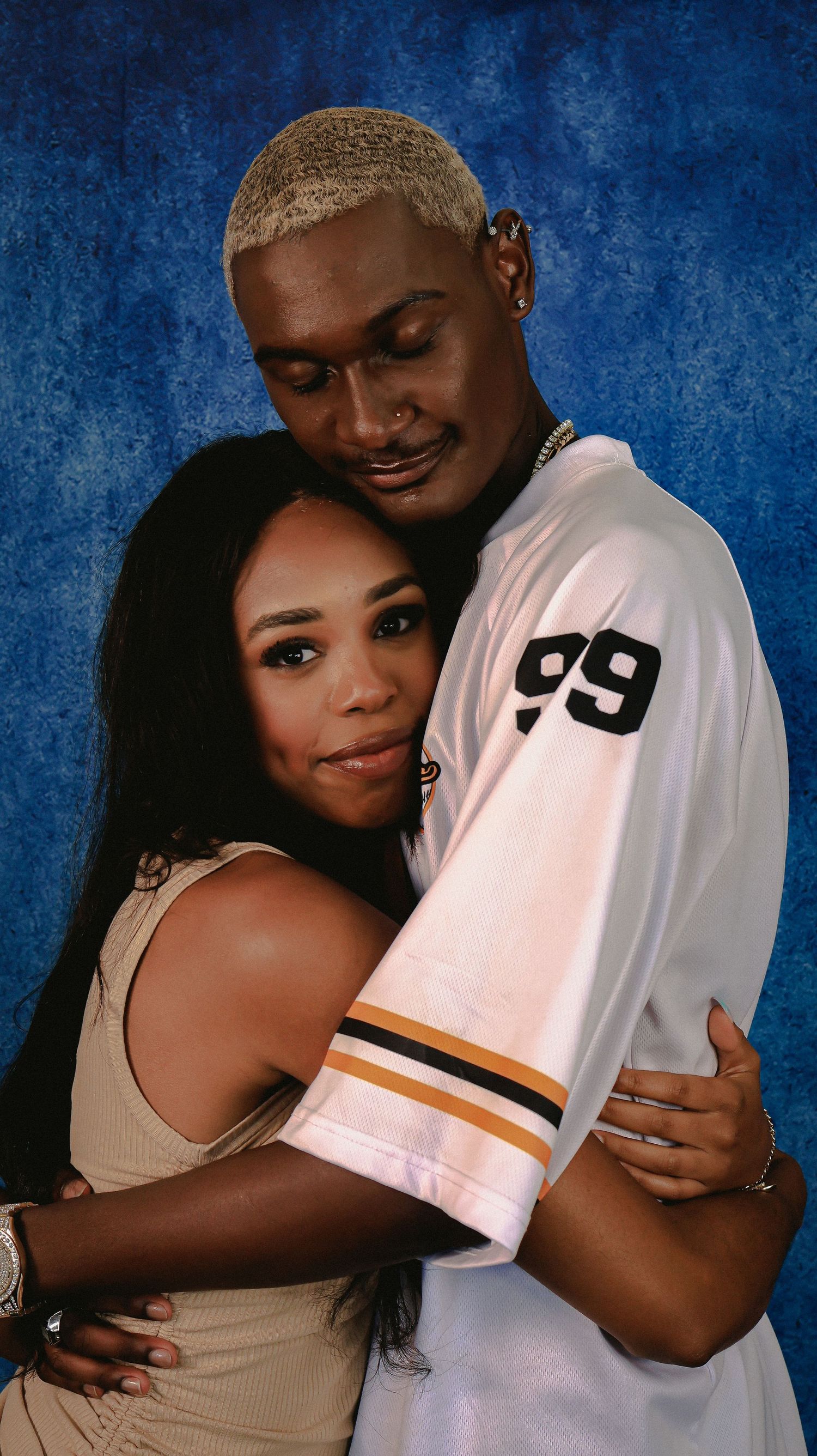 A romantic portrait of two people hugging with one wearing jersey number 99.