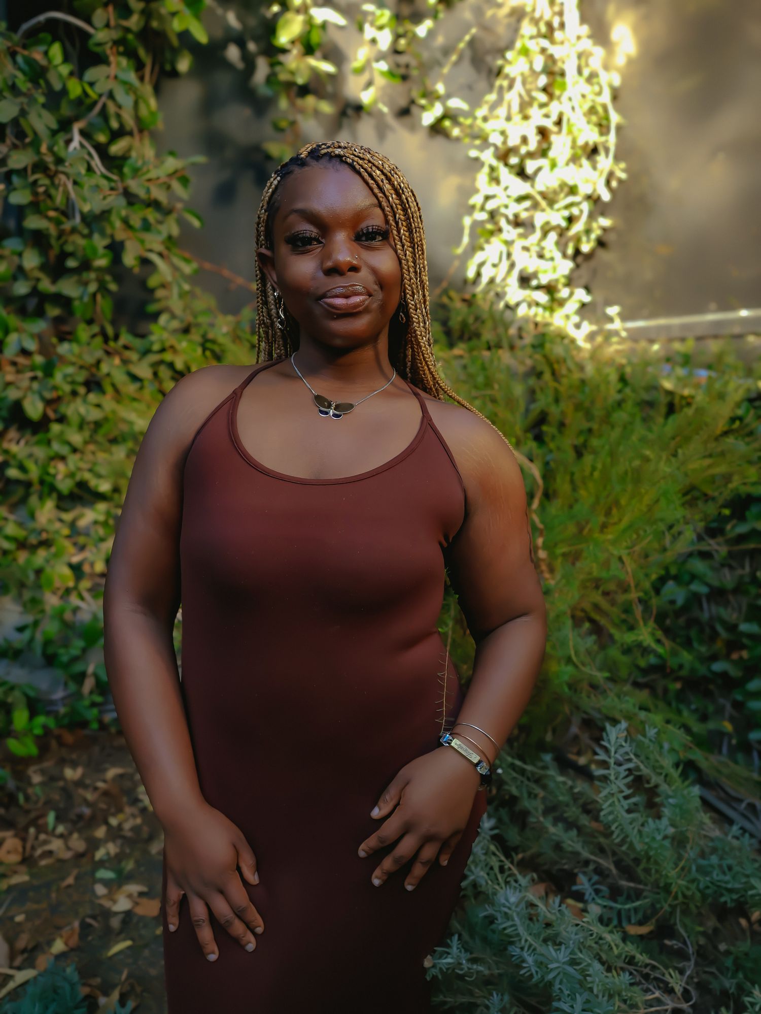 Outdoor portrait with natural sunlight filtering through garden foliage.