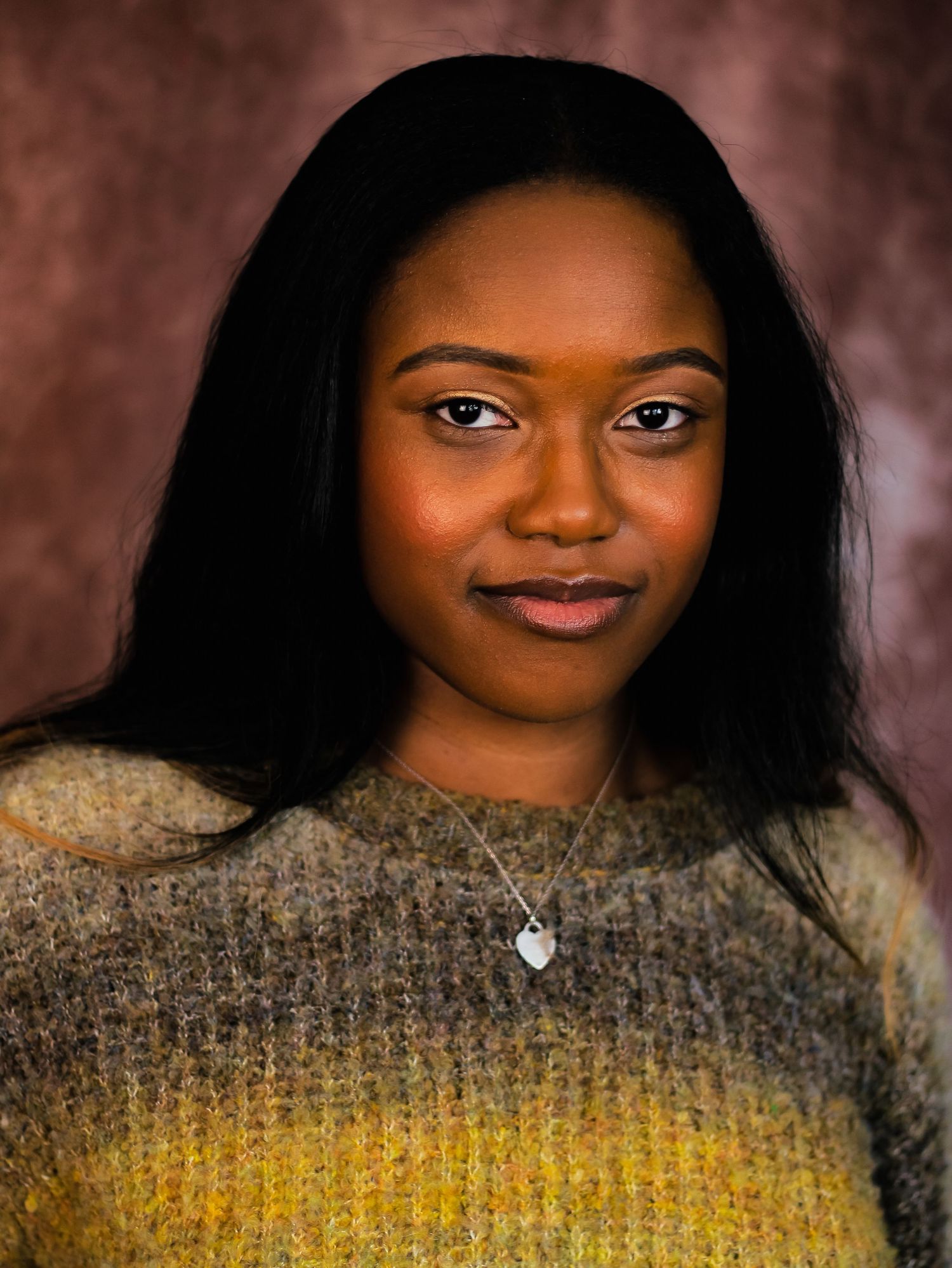 Portrait of person wearing yellow ombre sweater against brown background.