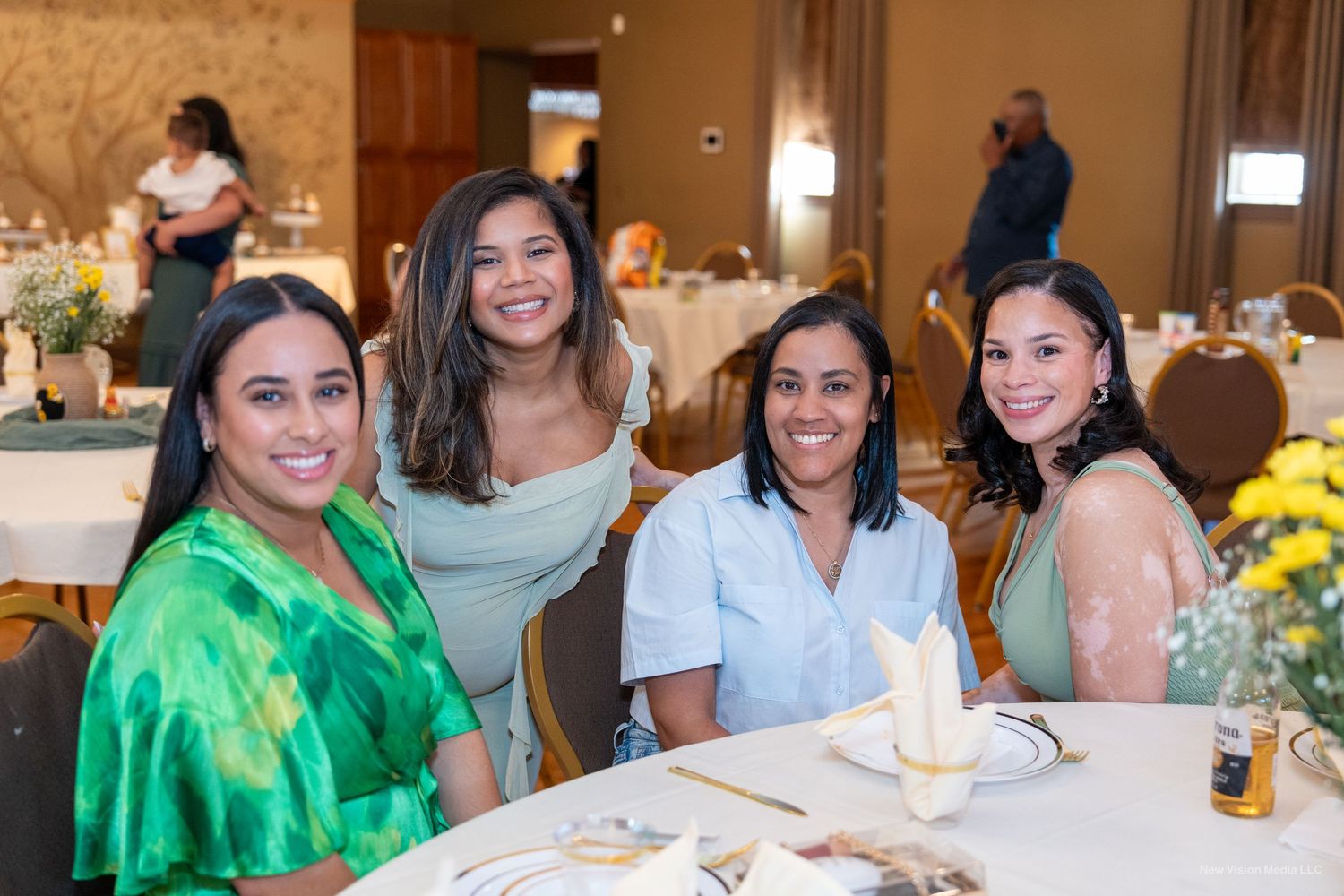 Group gathered around table at celebratory event with yellow floral centerpiece.