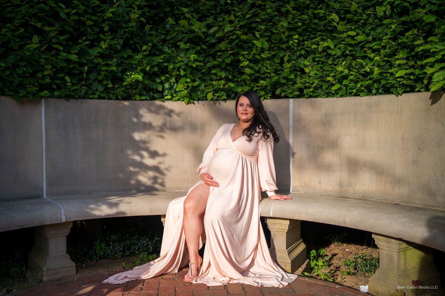 A soft pink dress flows elegantly across outdoor stone steps in a garden setting.