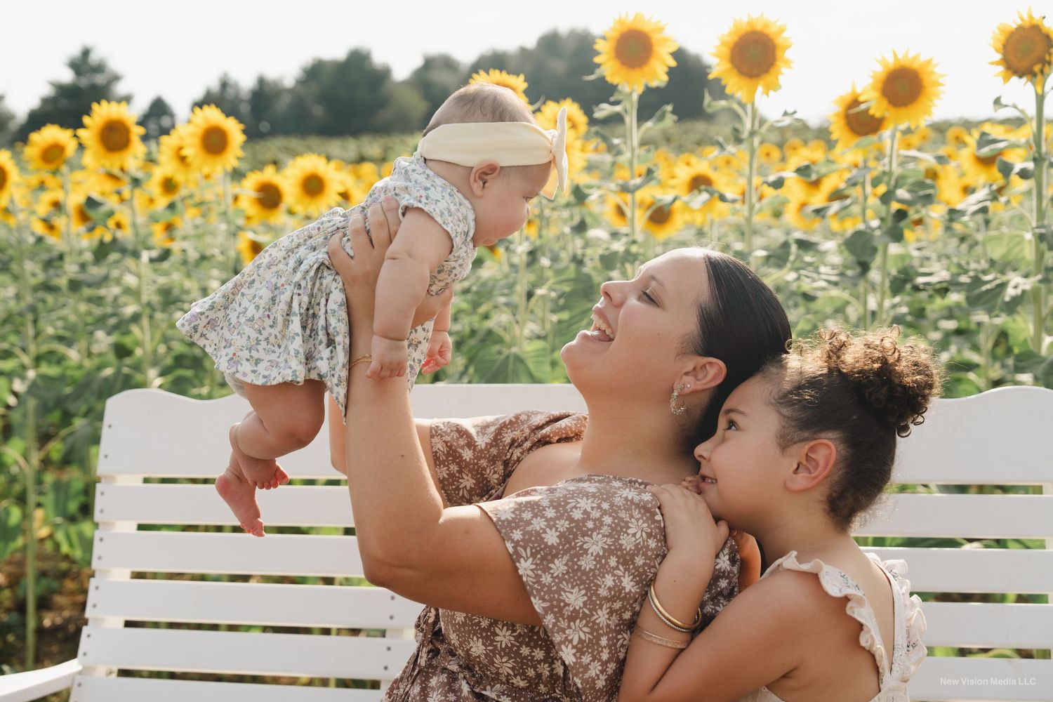 People enjoying a summer day on a white bench in front of blooming sunflower field.