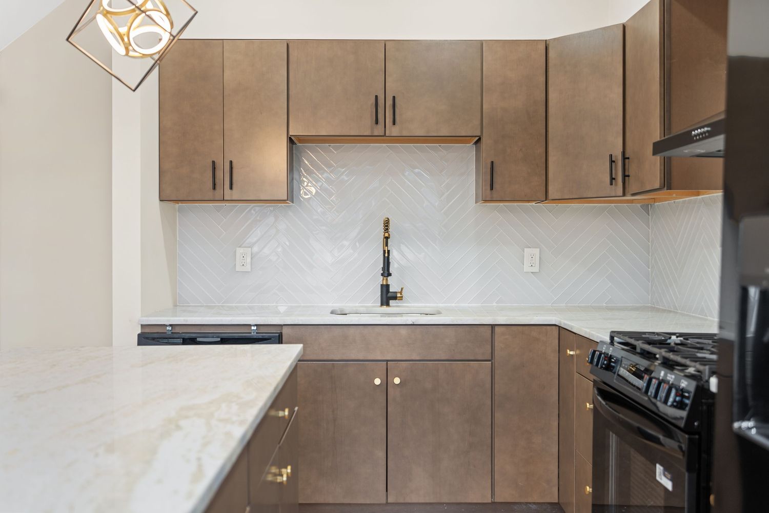 Modern L-shaped kitchen with brown cabinets, white countertops, and chevron tile backsplash.