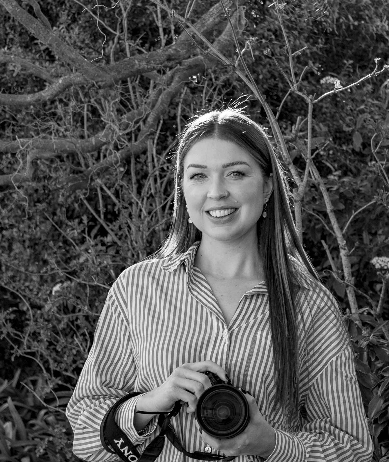 person holding camera standing in front of a tree