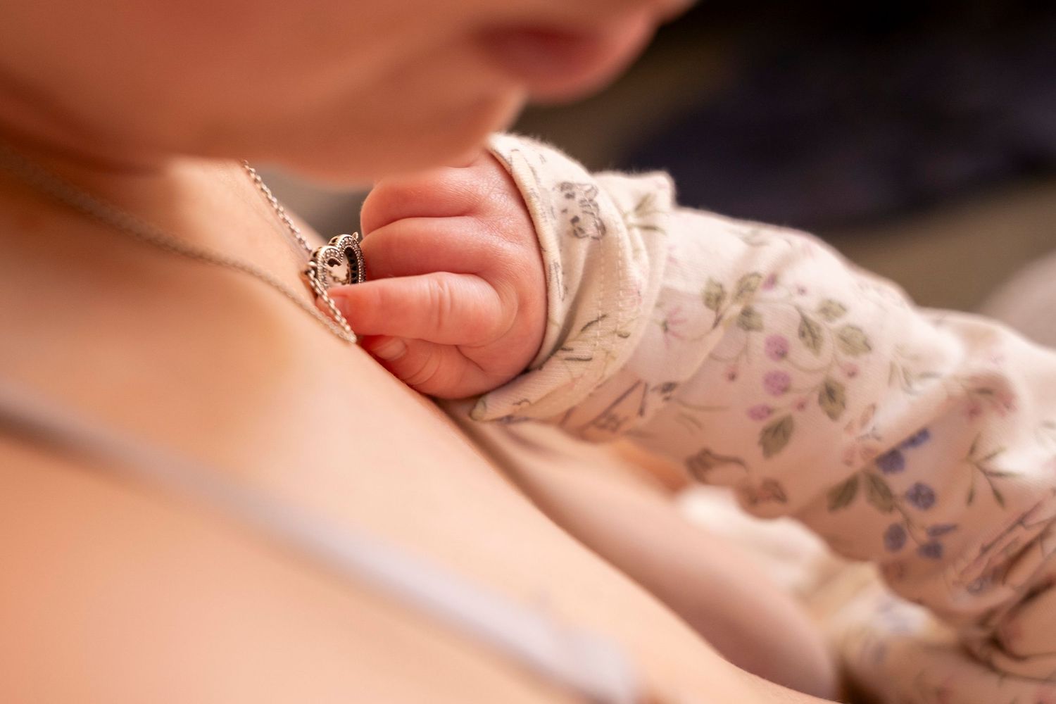 babies hand holding mothers necklace