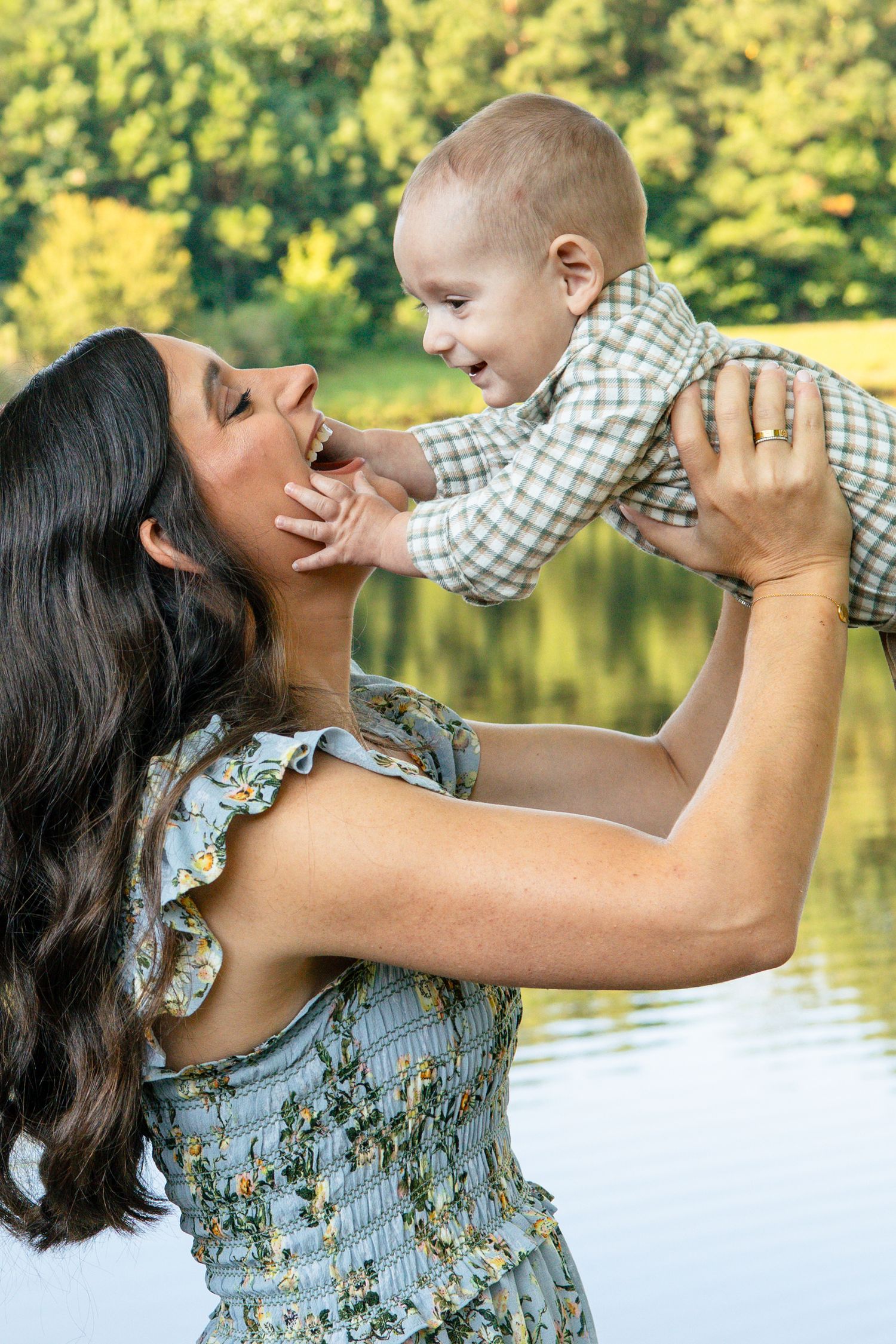 Joyful moment between parent and baby playing outdoors by lake.