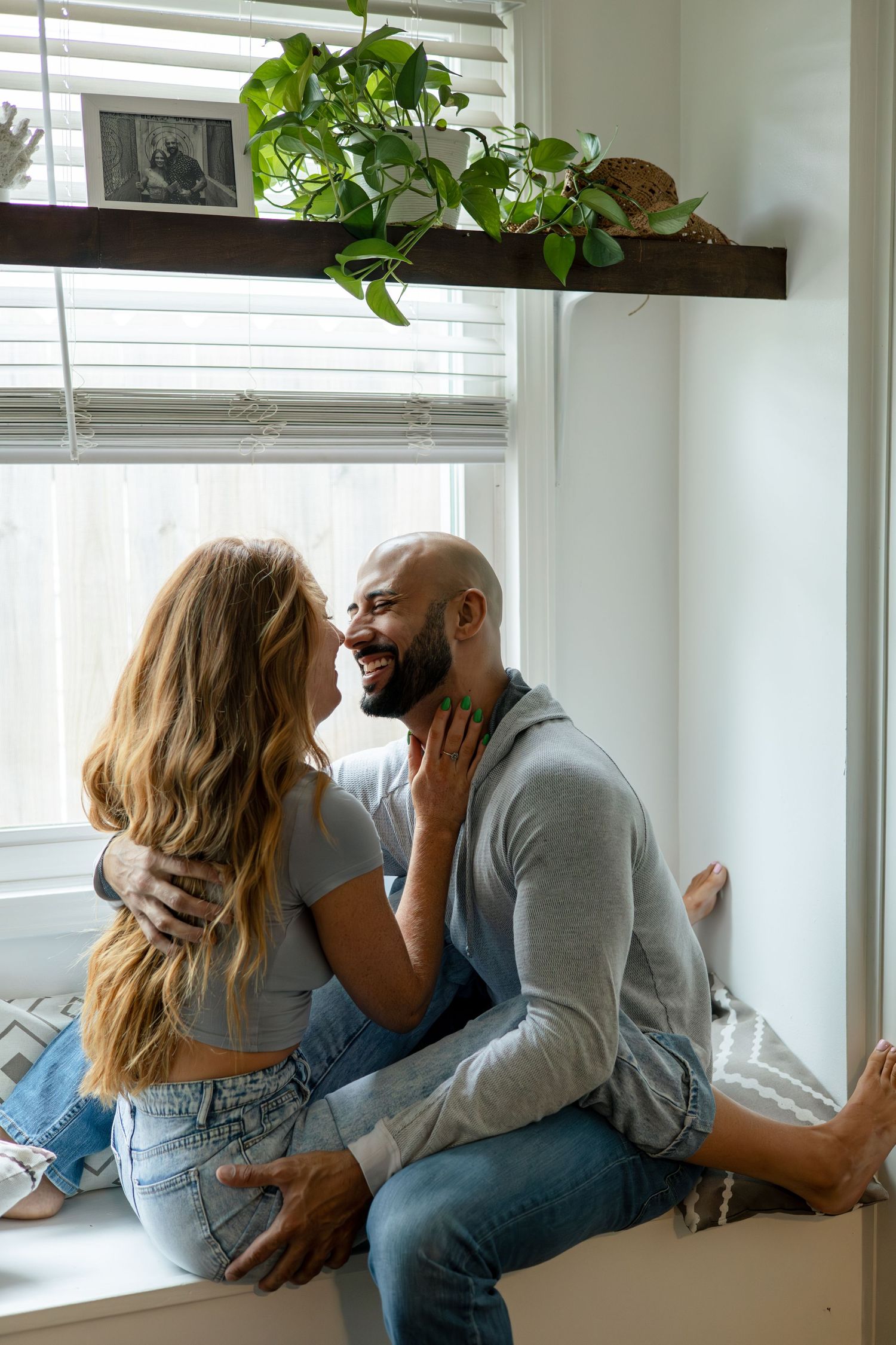 Couple sharing romantic moments by window with green plants.