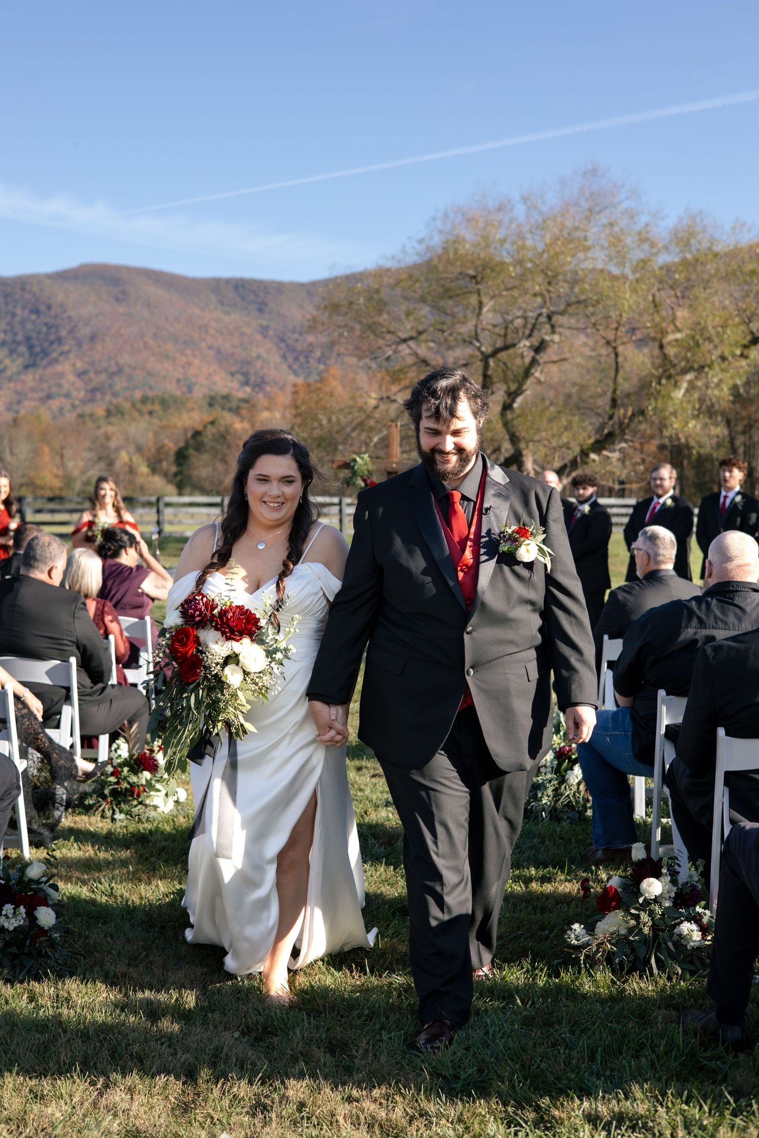 Wedding ceremony taking place outdoors with mountain views and fall foliage in the background.