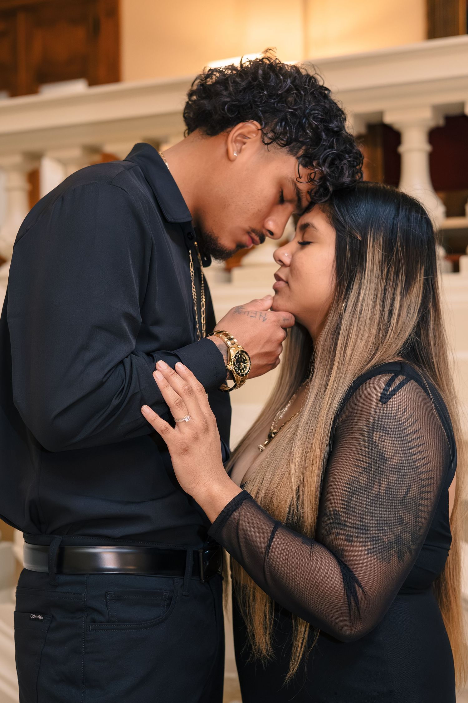 Intimate couple shares romantic moments in formal attire against white architectural backdrop.
