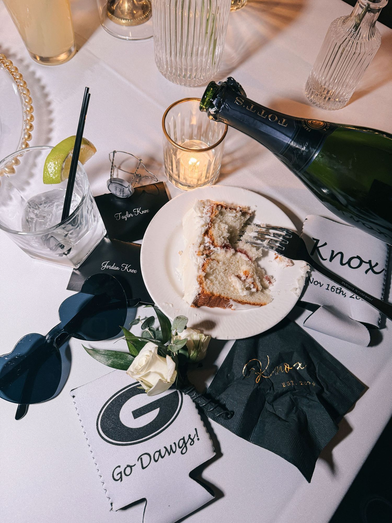 Wedding reception table setting with cake slice, champagne and Georgia Bulldogs fan merchandise.