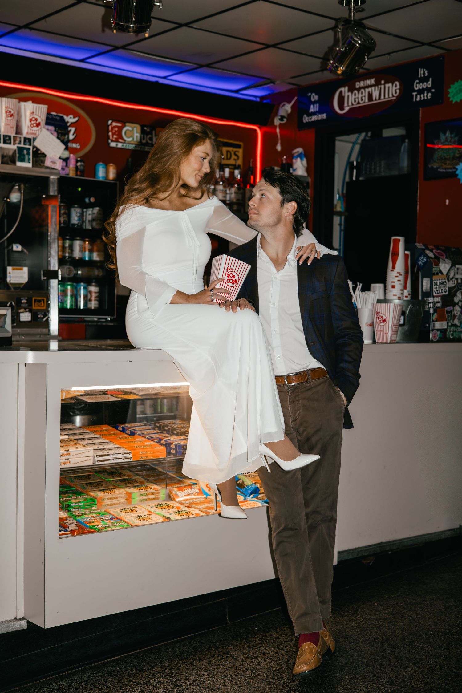 Couple sharing intimate moments at a movie theater concession stand.