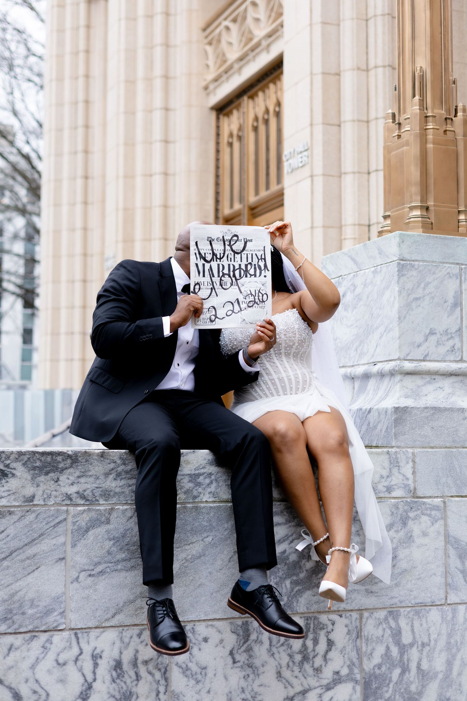 Couple sitting on marble steps holding signs in a romantic wedding photo sequence.