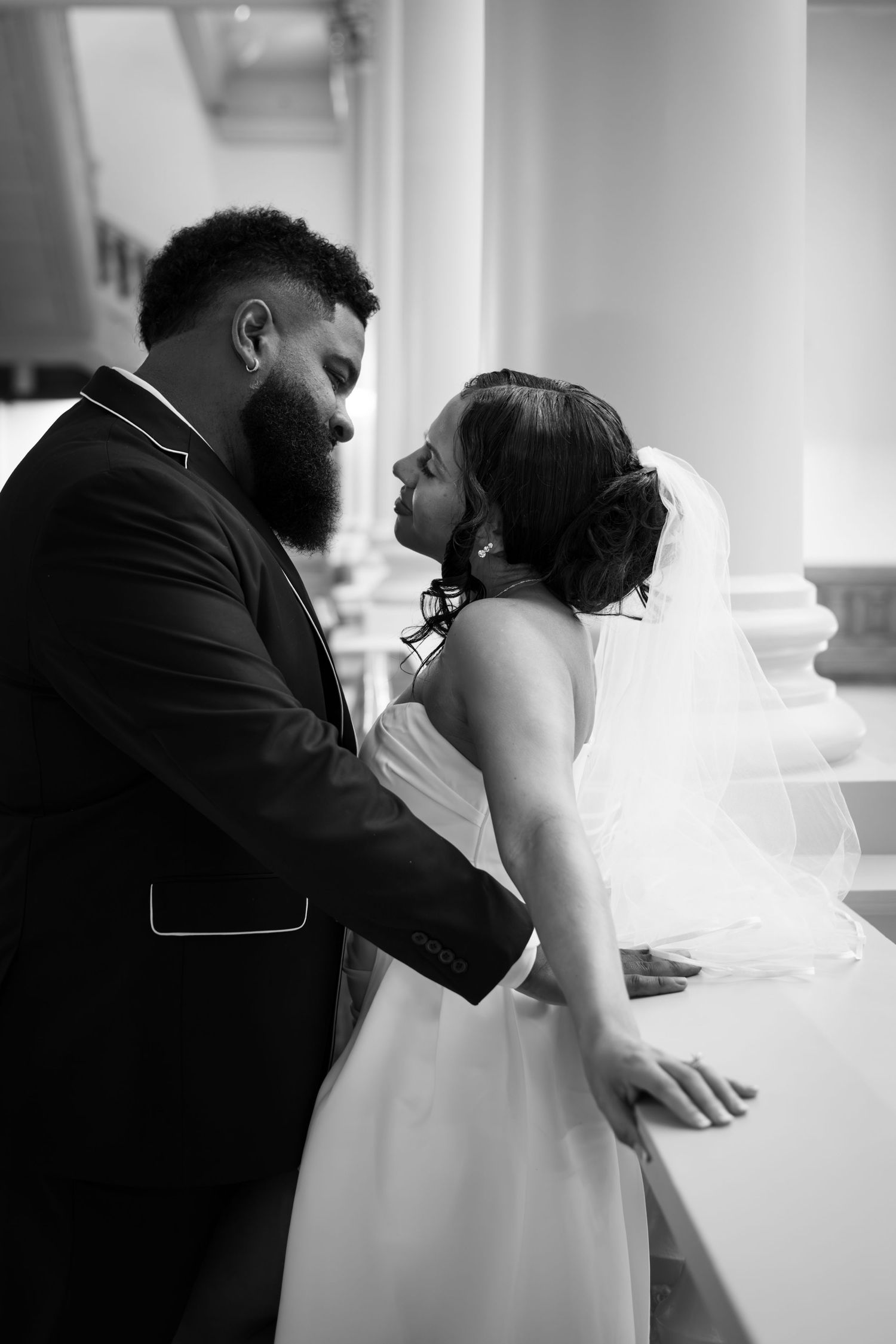 An intimate black and white wedding portrait capturing a tender moment between newlyweds.