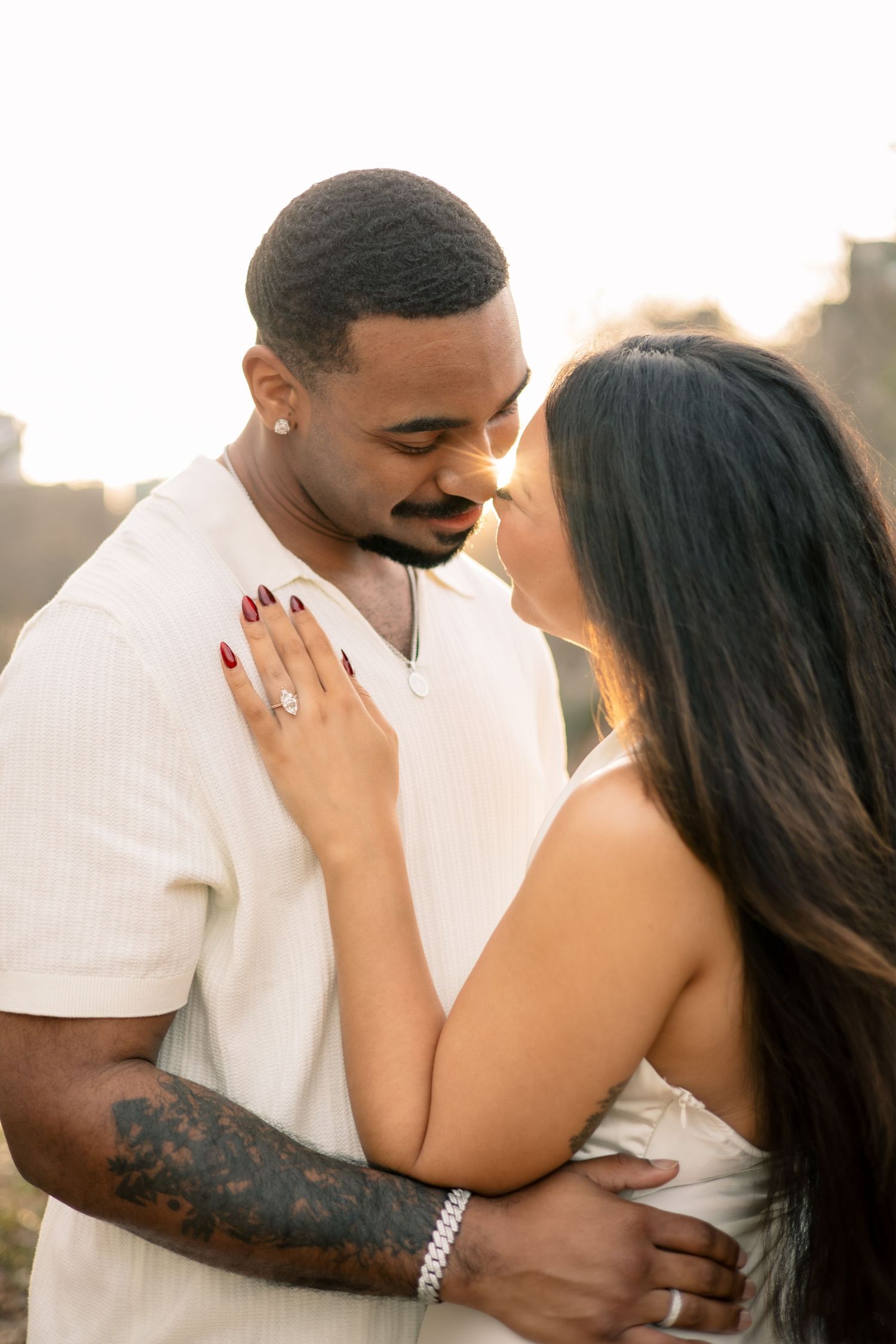 A romantic couple shares intimate moments in a series of engagement photos wearing white against a soft blurred background.