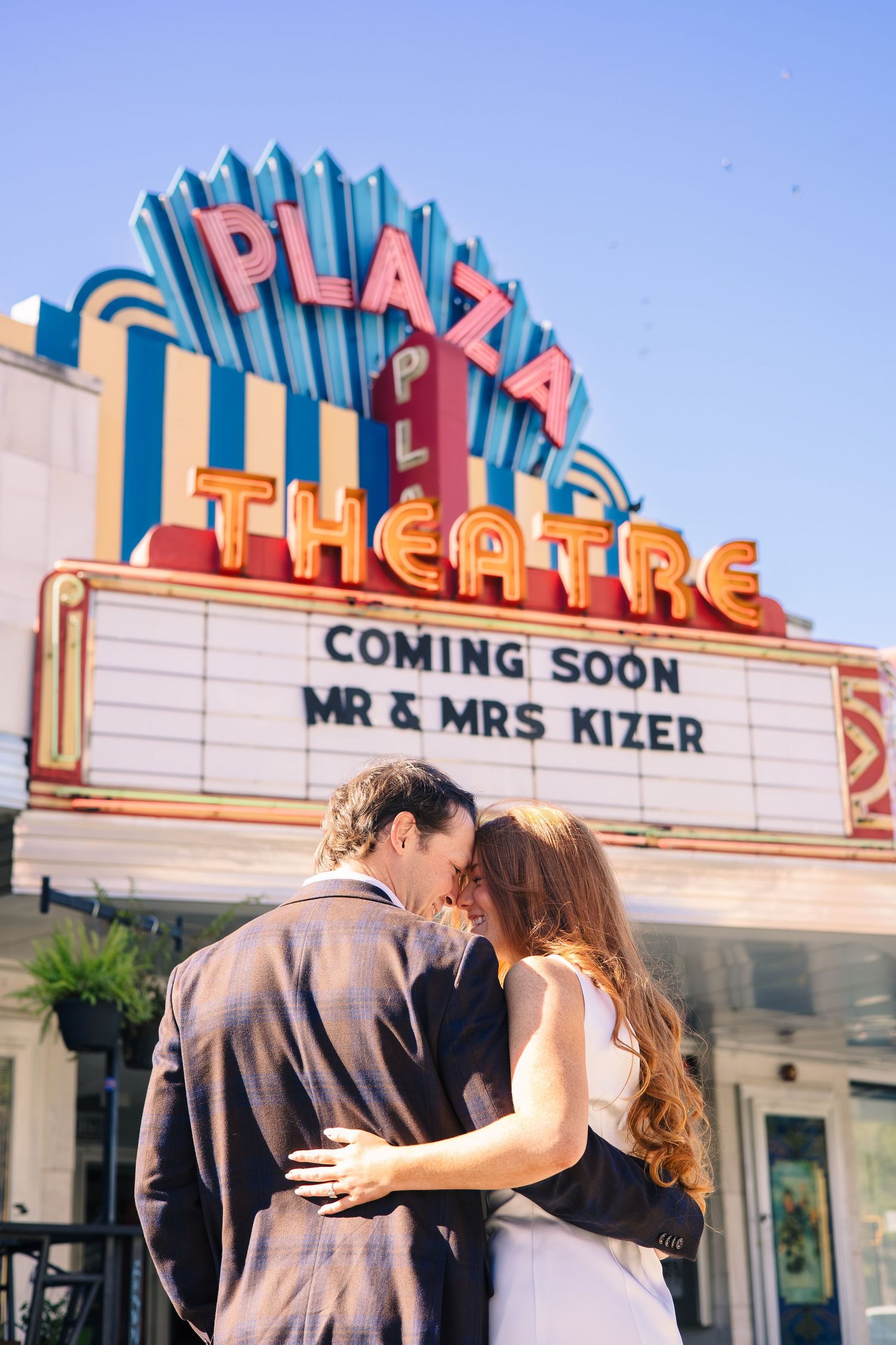 Romantic couple poses for photos in front of a vintage Plaza Theatre marquee.