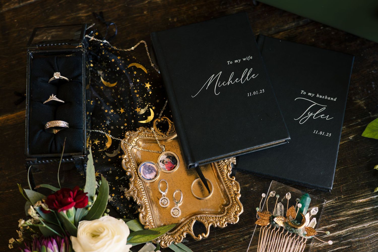 Wedding stationery and decor elements arranged on dark wooden surface with floral accents.