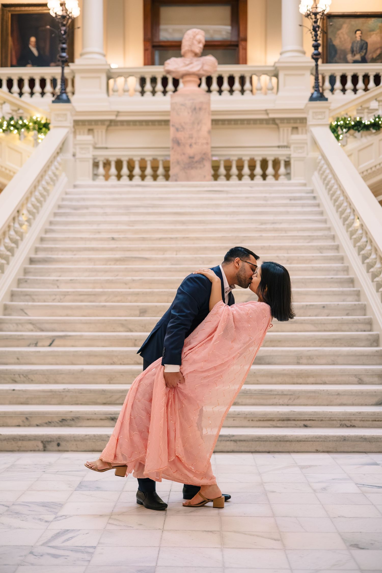 A romantic dip pose on elegant marble stairs in a grand building.