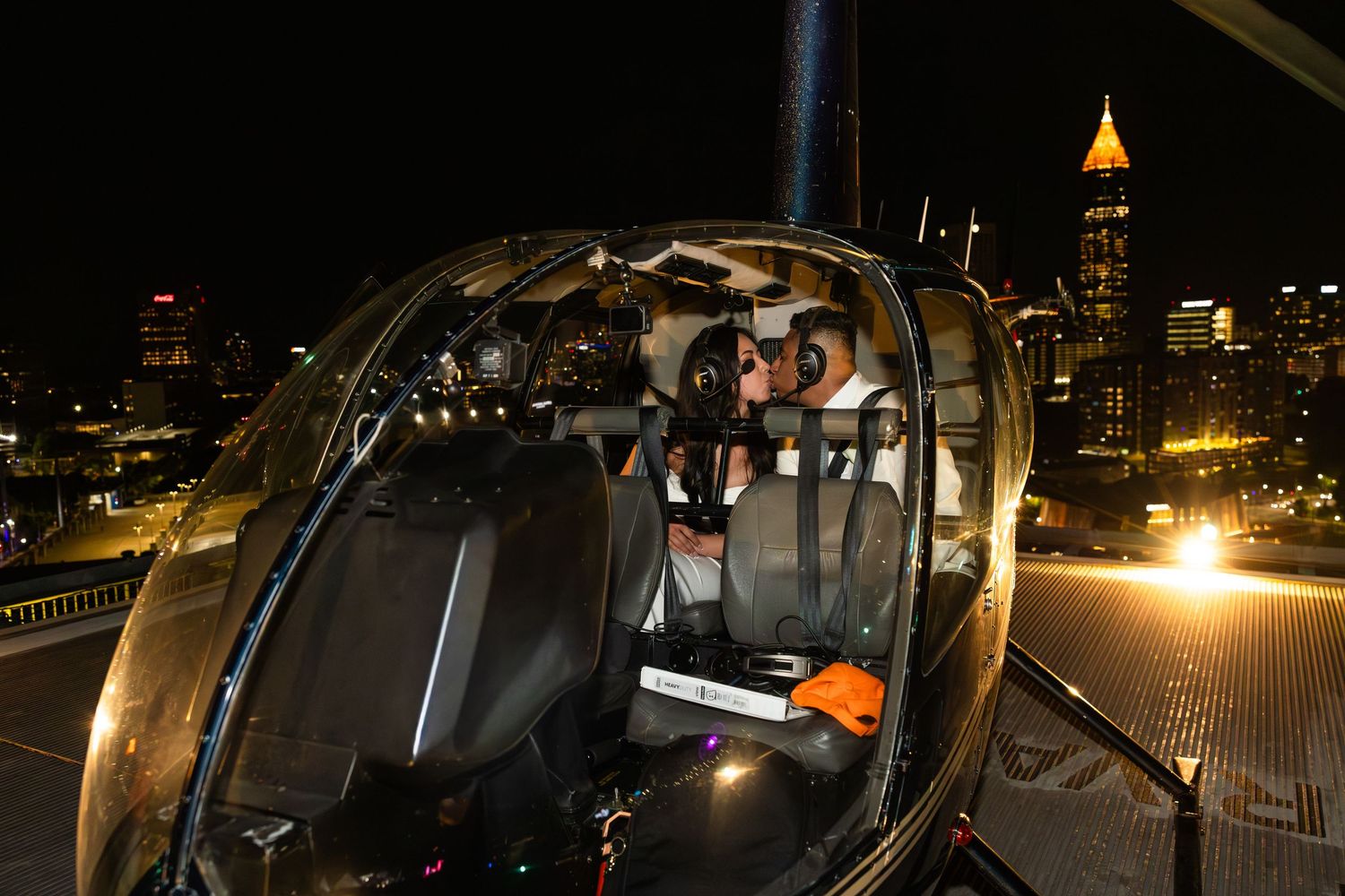 Newlywed couple sitting in helicopter at night with Atlanta cityscape behind them.