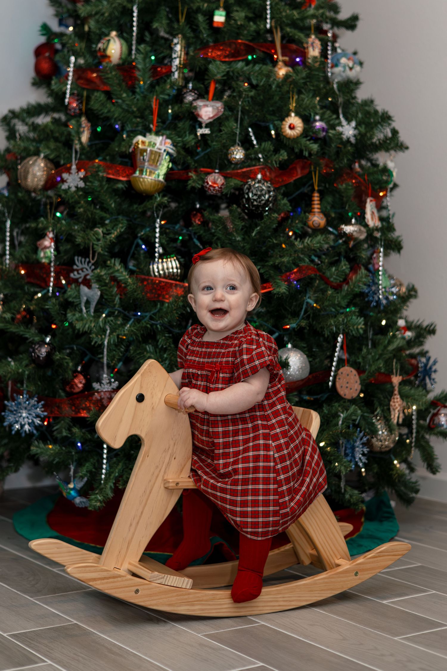 Festive holiday scene with wooden rocking horse by decorated Christmas tree.