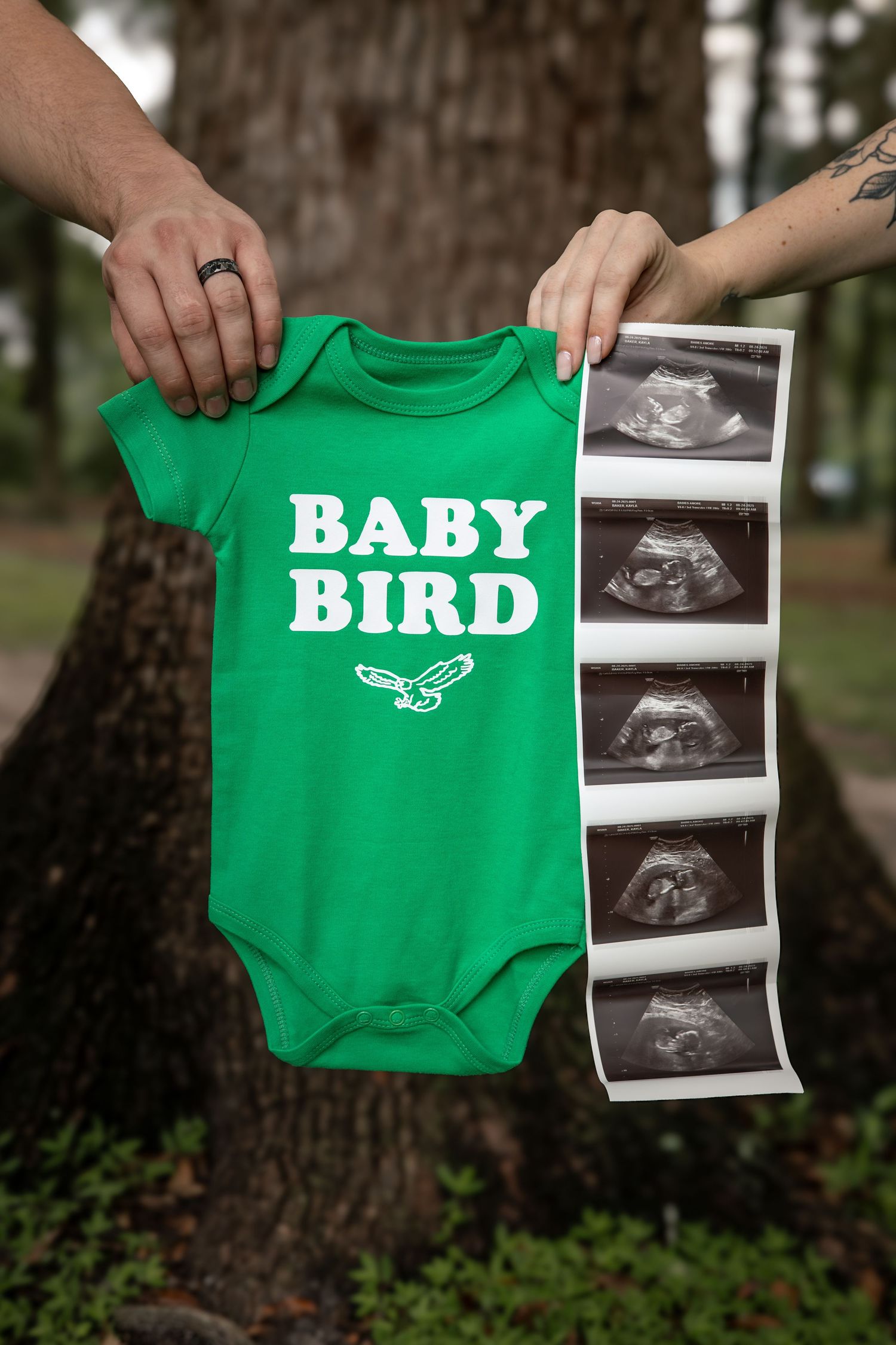 Hands hold a green baby onesie with 'BABY BIRD' text next to ultrasound photos.