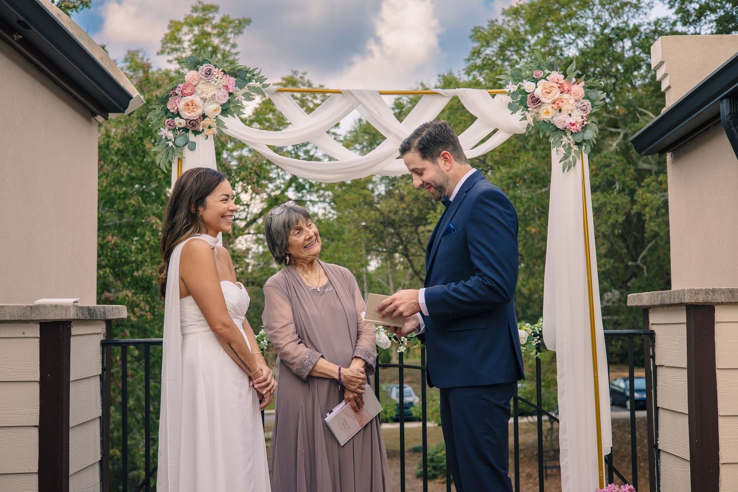 Outdoor wedding ceremony setup with white arch and floral decorations.