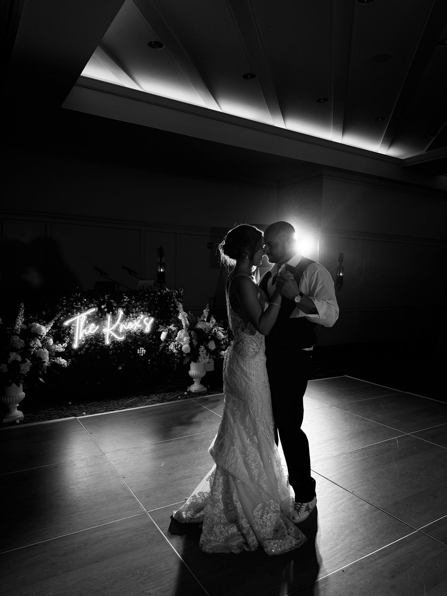 A dramatic black and white first dance photo with backlighting creating a romantic silhouette.