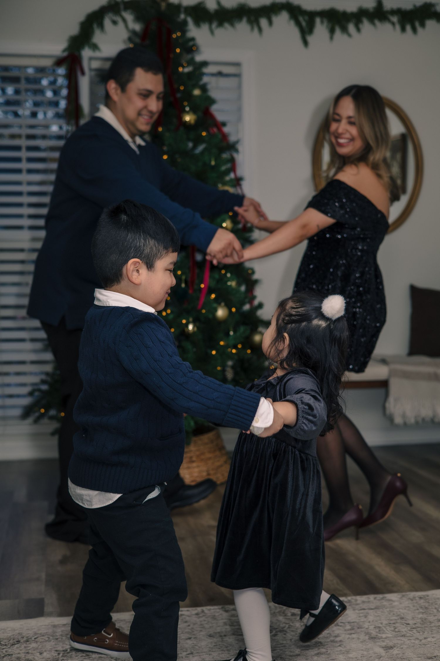 Holiday celebration with dancing and festive outfits by Christmas tree.