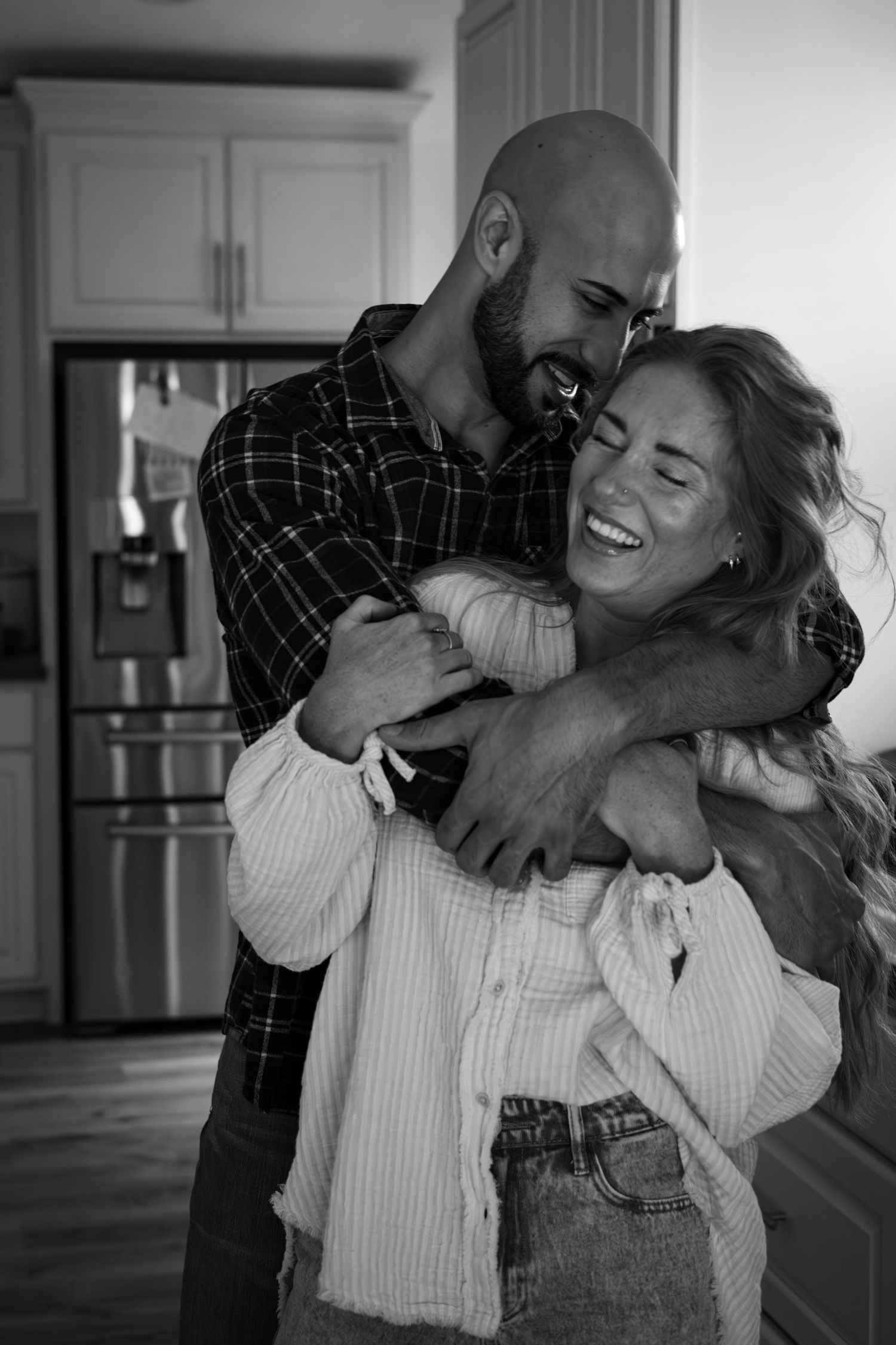 Playful couple sharing intimate moments in modern kitchen setting.
