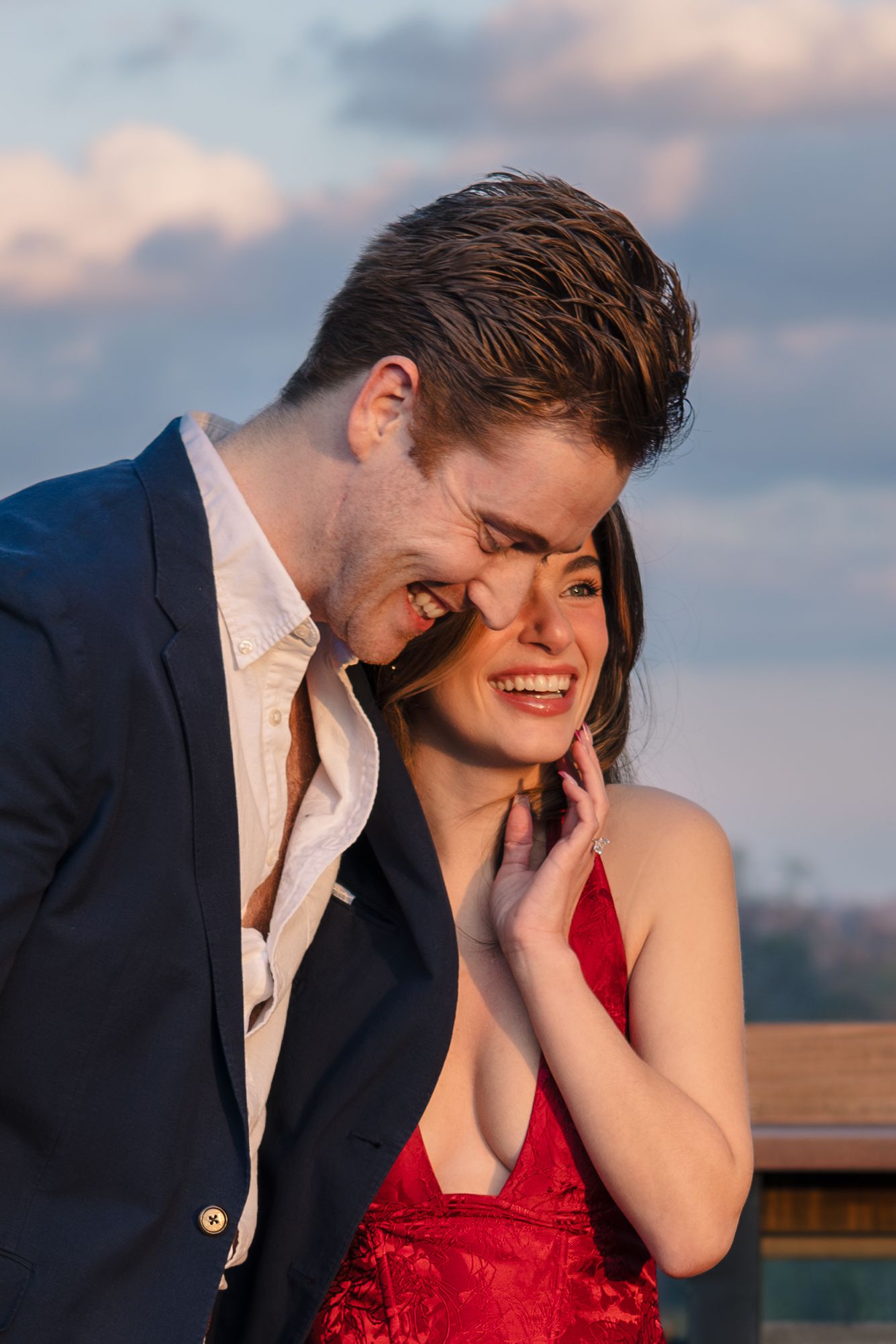 Couple sharing joyful laughter and intimate moments during sunset on a rooftop.